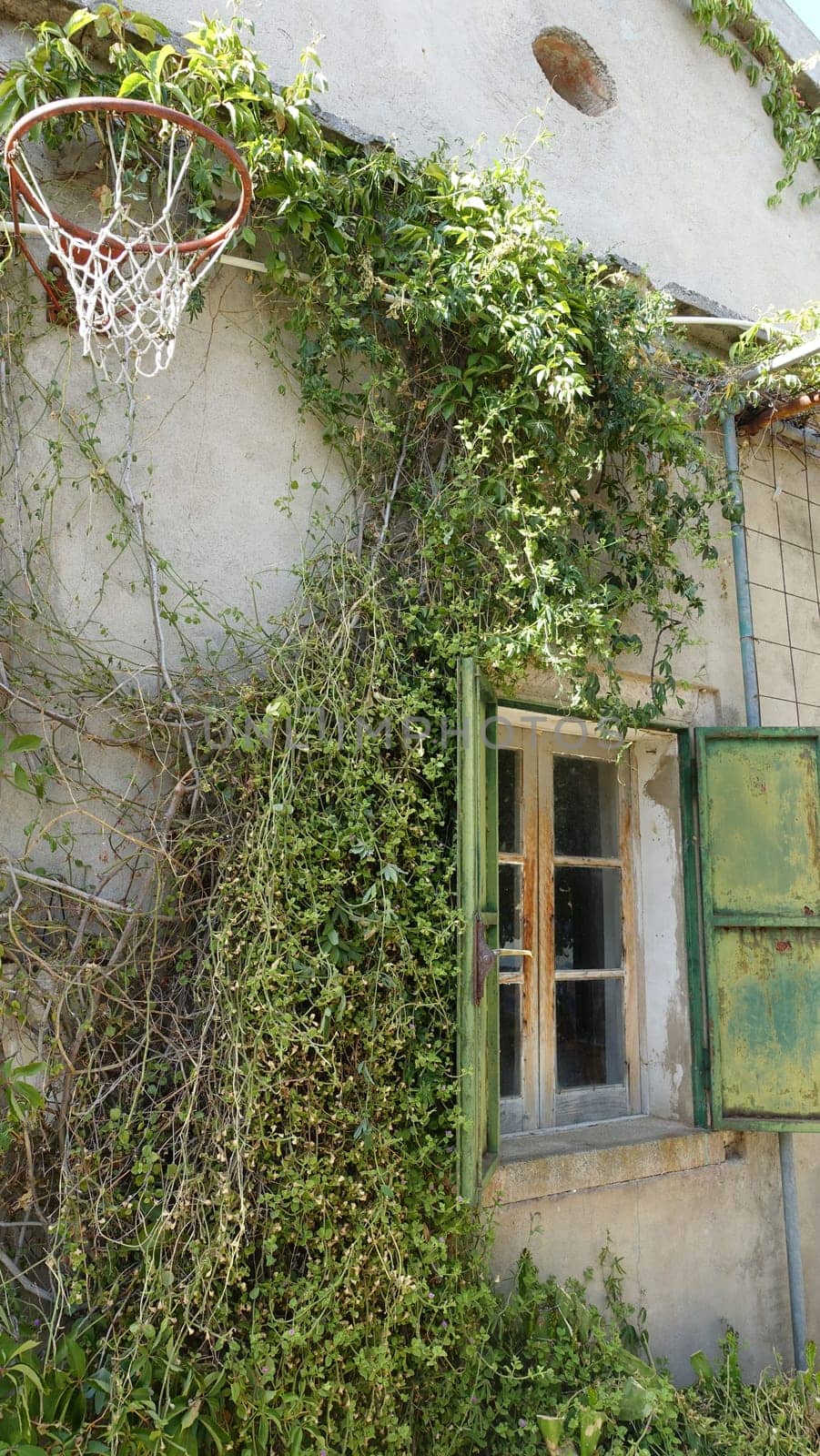 The glimpse of an old country house with an old basketball hoop on the wall by Jamaladeen