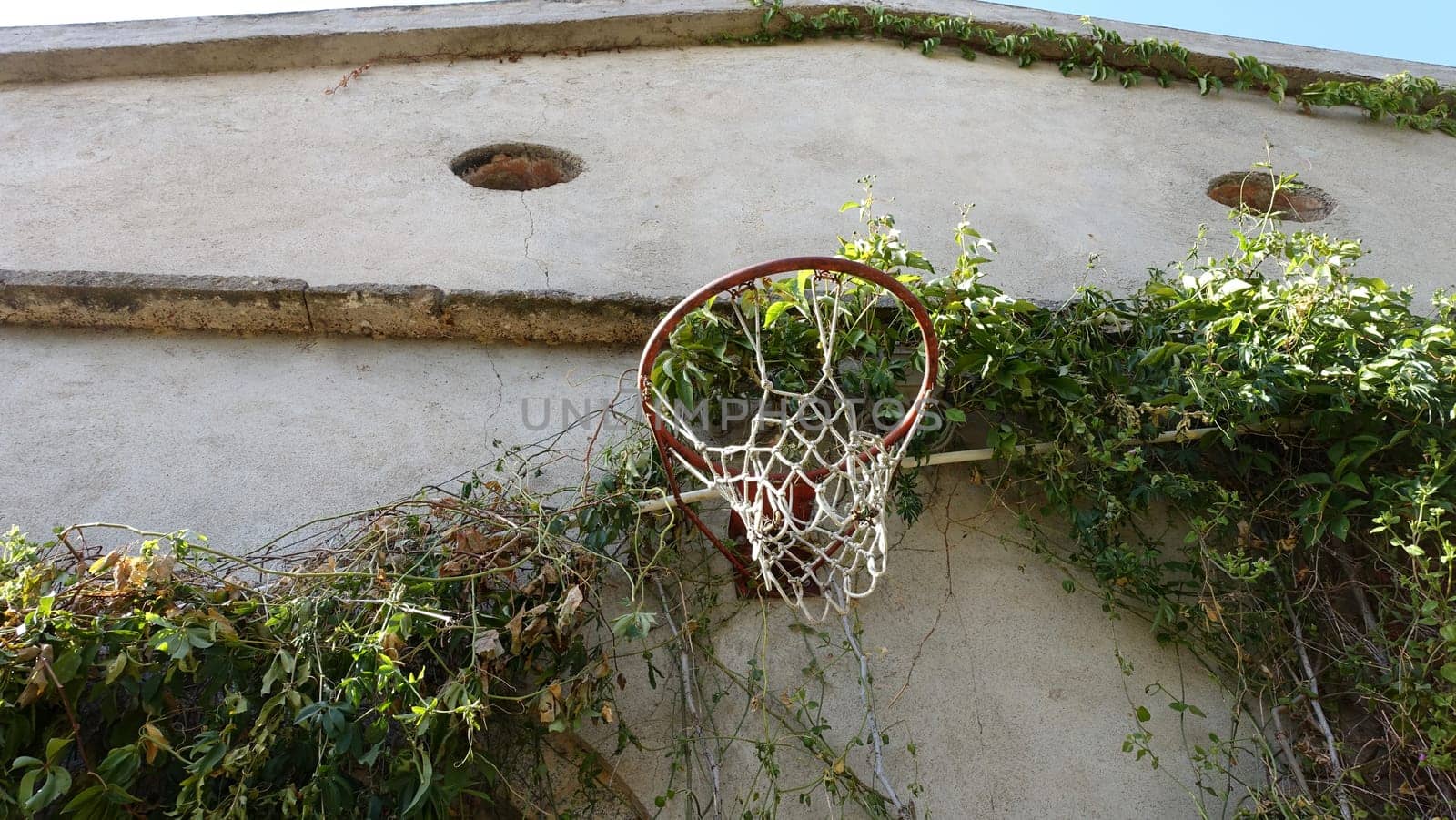 An old basketball hoop on the wall of an old country house. by Jamaladeen