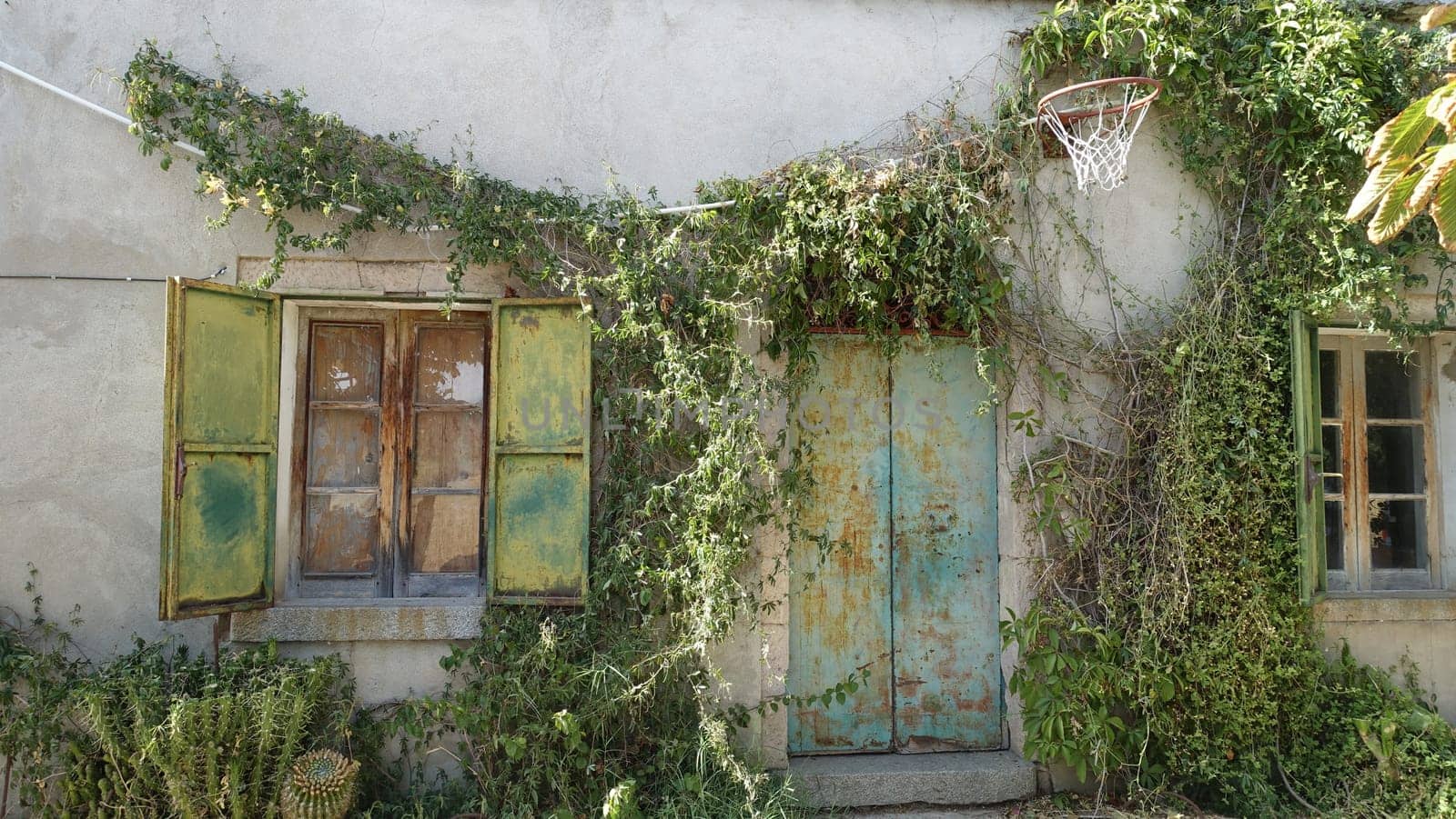 The facade of an old country house with an old basketball hoop on the wall by Jamaladeen