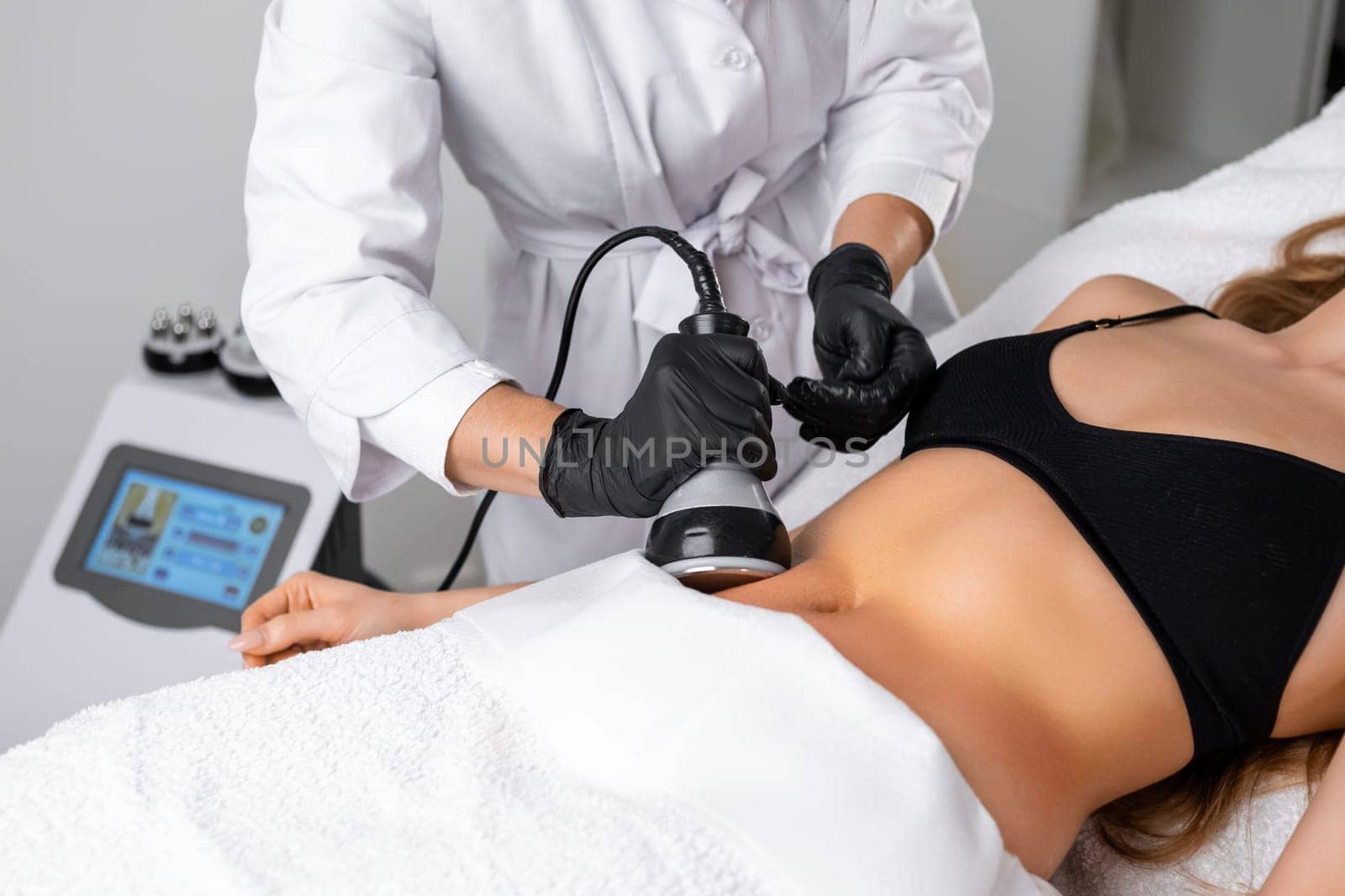 Young woman engaging in ultrasound cavitation therapy for body contouring by vladimka