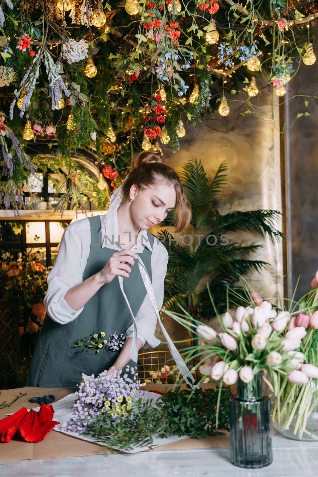 A woman in her florist shop collects bouquets of flowers. The concept of a small business. Bouquets of tulips for the holiday on March 8