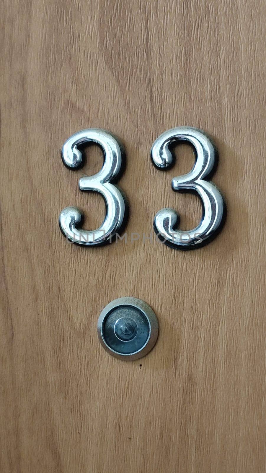 numbers 33 on a white exterior apartment door, symbol objects, sky. High quality photo