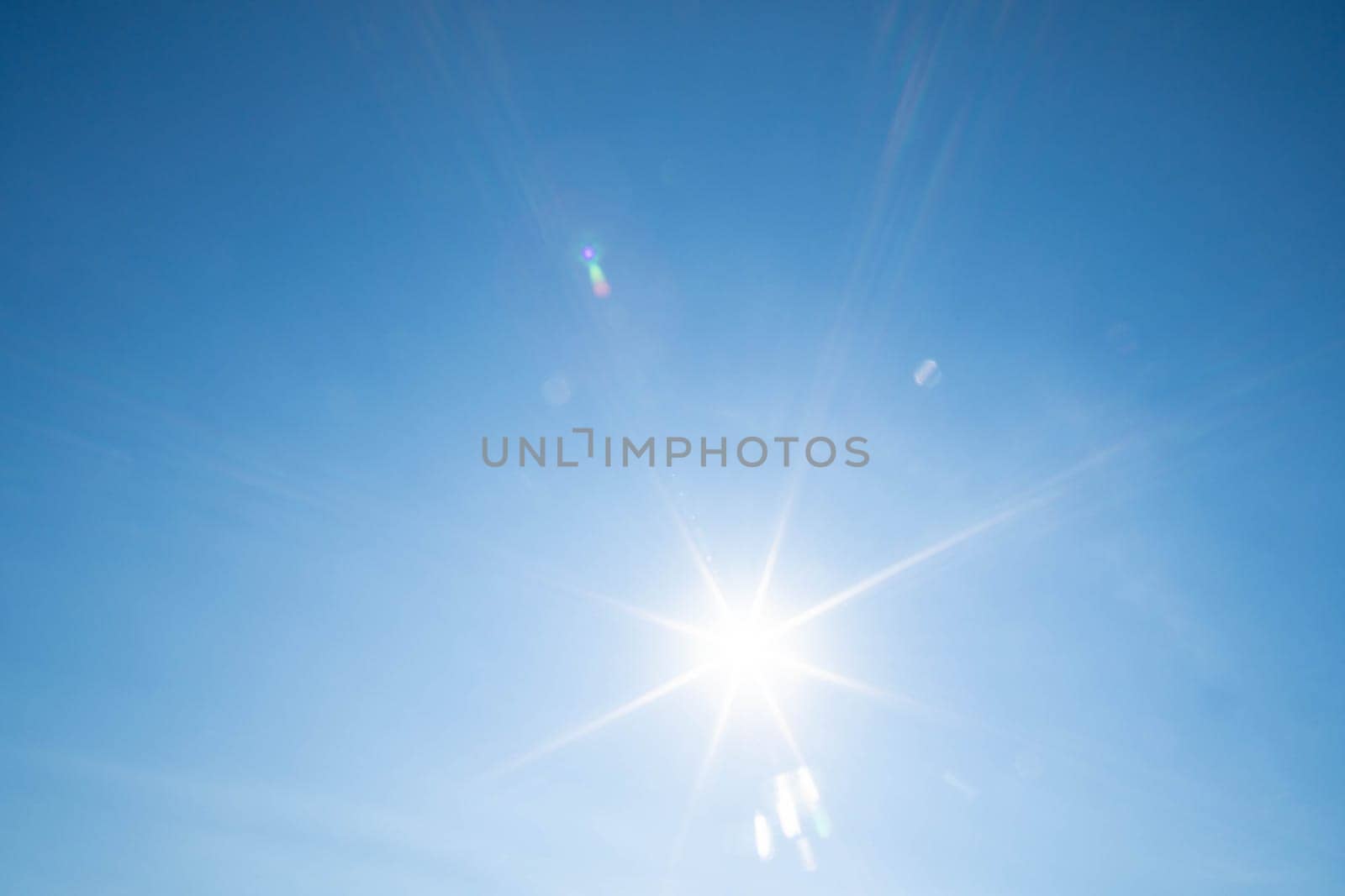 Sharp sunbeams on a cloudless day in summer and holiday time. Clear blue sky background.