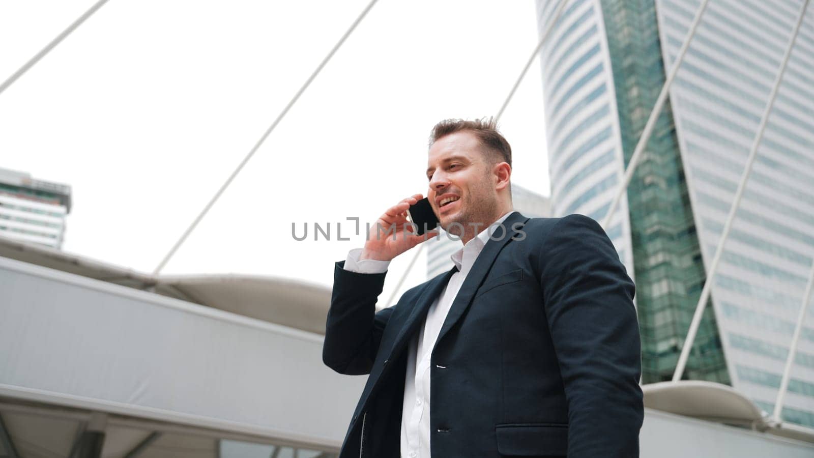 Skilled businessman calling his colleague while standing at urban city. Urbane. by biancoblue