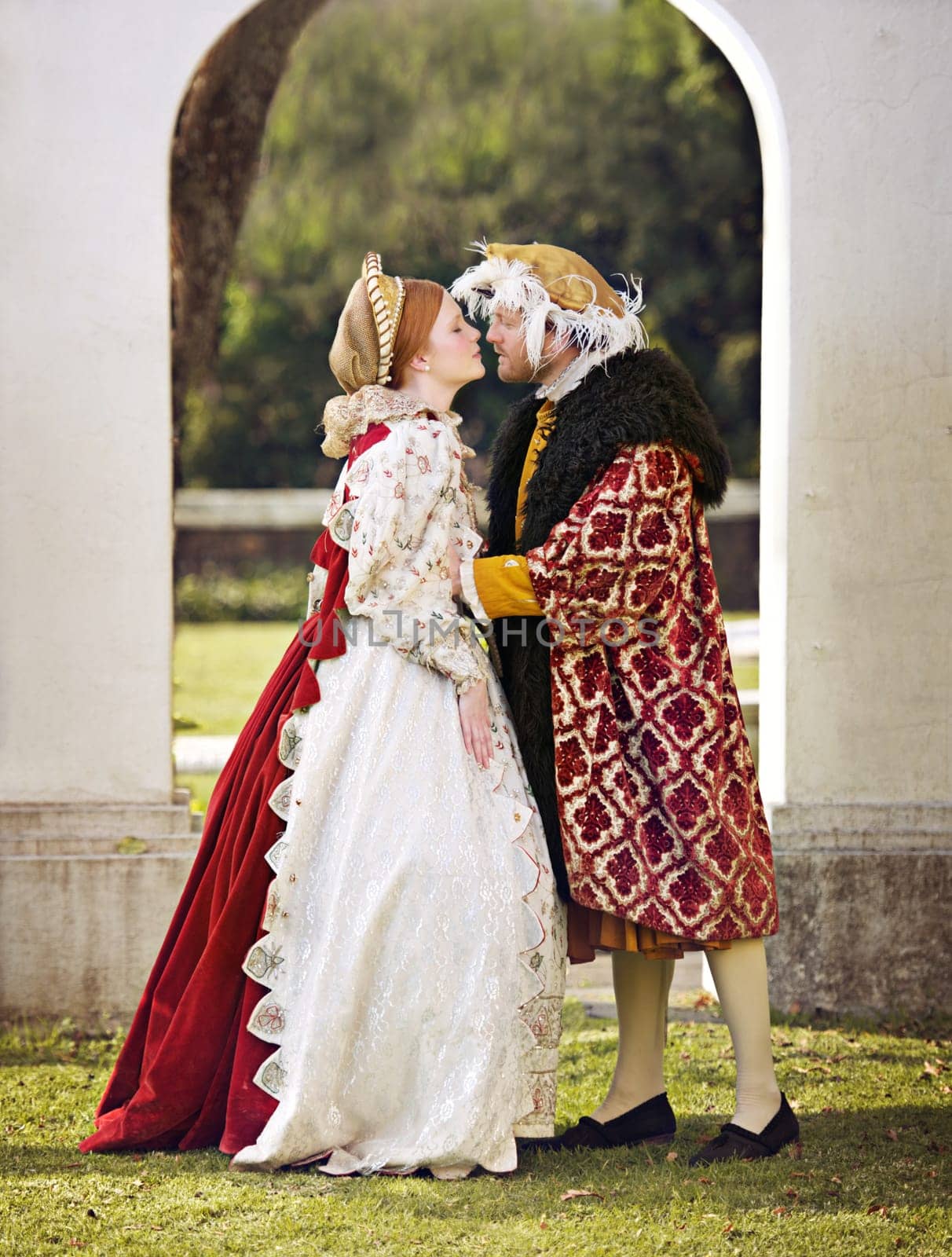 Medieval, king and couple kiss in marriage with renaissance fashion outdoor with marriage and love. Vintage, garden and royal leader with queen together on lawn with victorian and theater costume by YuriArcurs