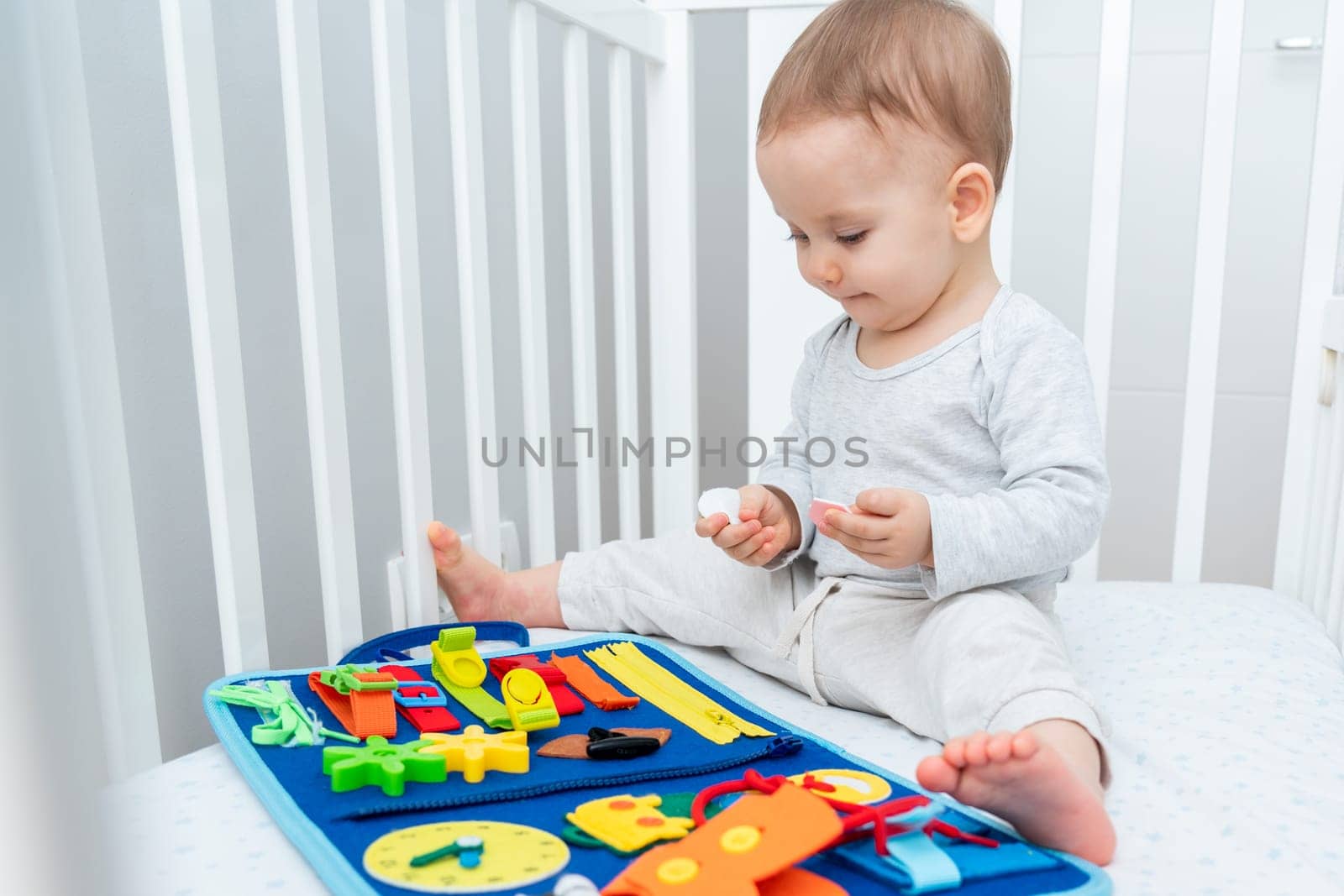 Baby happily plays with felt board in crib by Mariakray