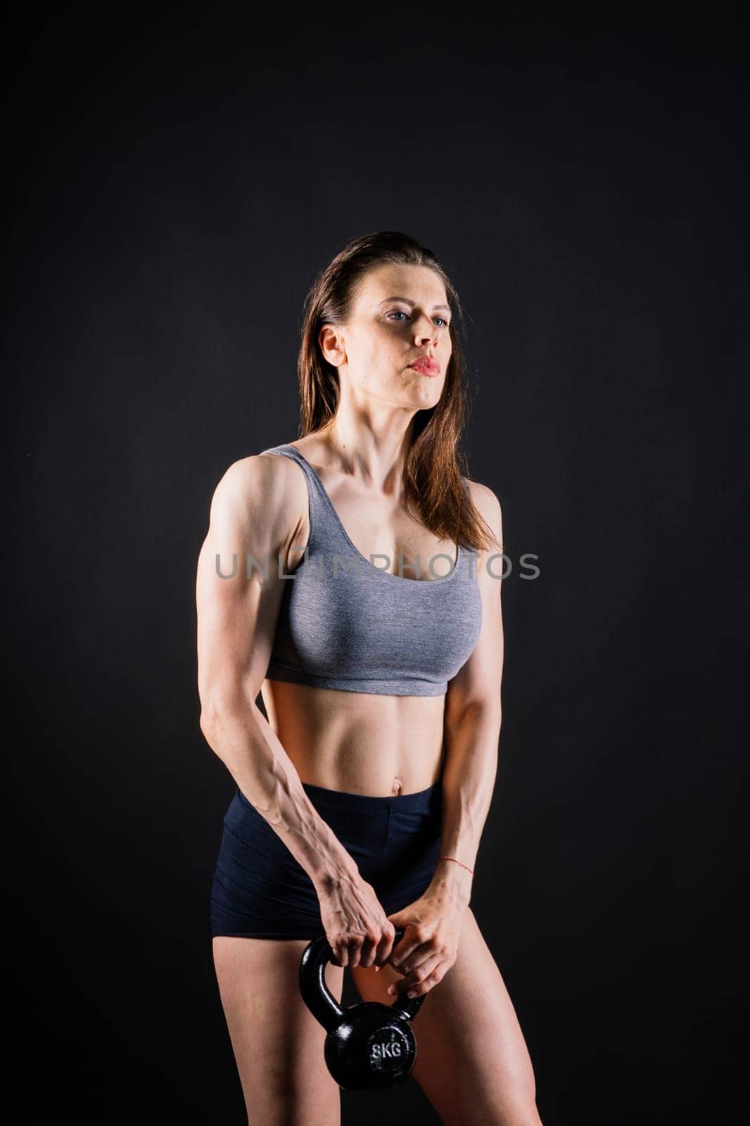 Young female doing swing exercise with a kettle bell. Fitness woman by Zelenin