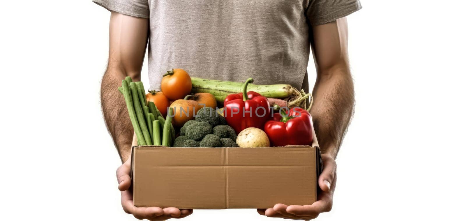 A man is holding a box of vegetables. The box contains broccoli, carrots, and peppers