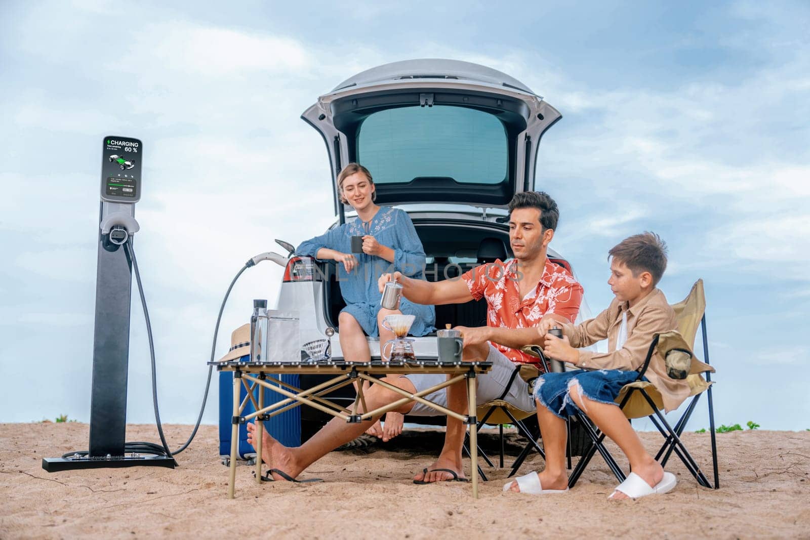 Family vacation trip traveling by the beach with electric car, happy family recharge EV car, enjoying outdoor camping coffee. Seascape travel and eco-friendly car for clean environment. Perpetual