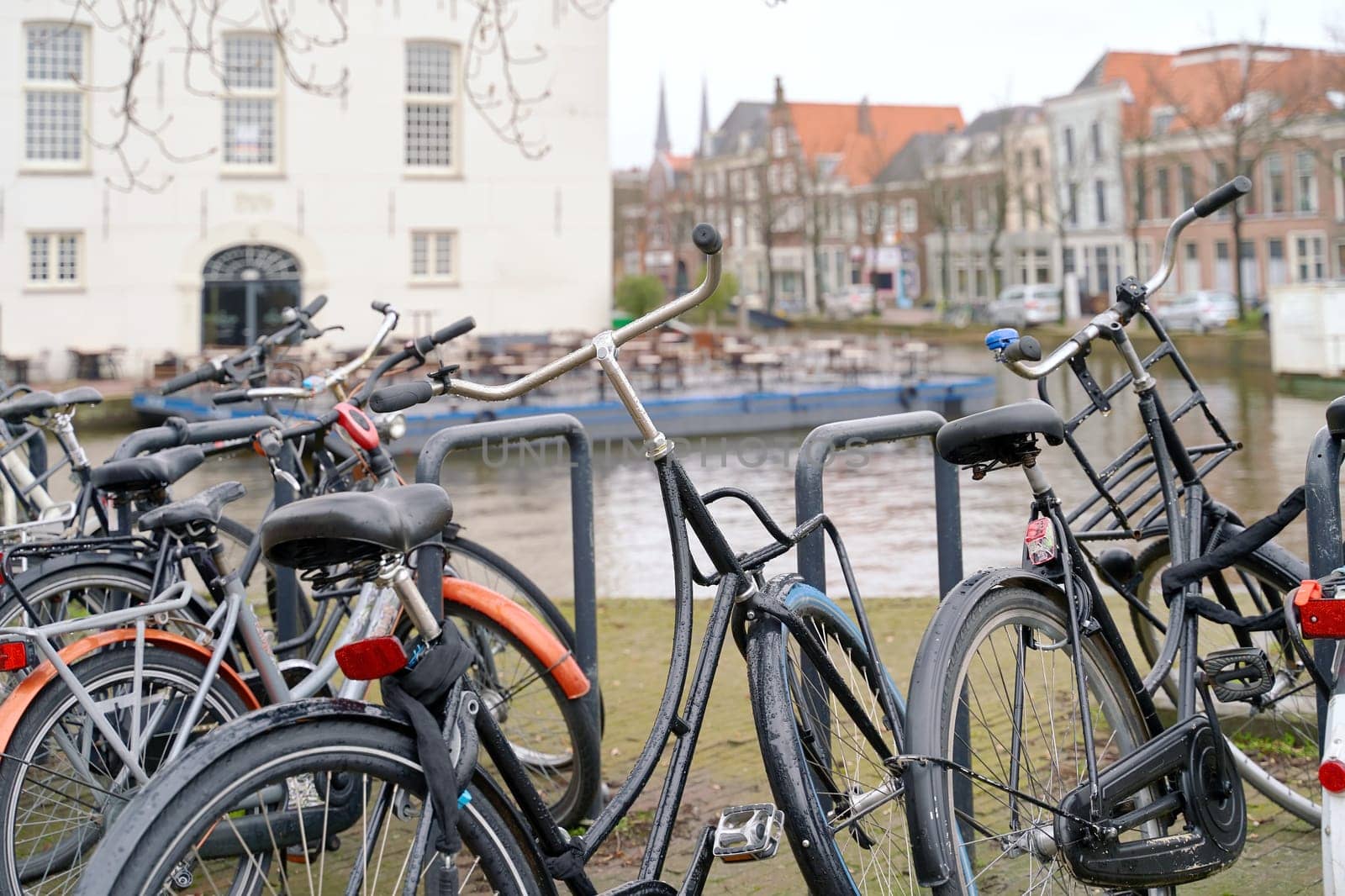 Delft, Netherlands. Bicycles parked alongside a channel on beautiful old buildings background. by berezko