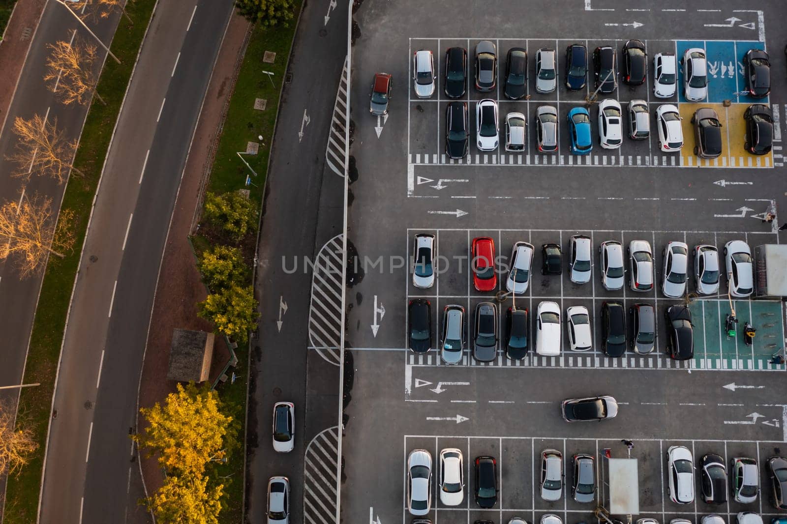 Aerial view of large car parking with many parked cars. Car park near shopping mall with lines and markings for vehicle places and directions