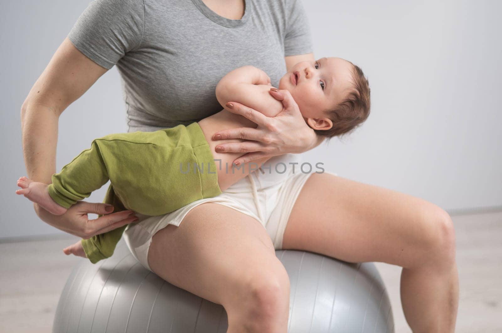 A faceless woman rocks her newborn son on a fitball. by mrwed54