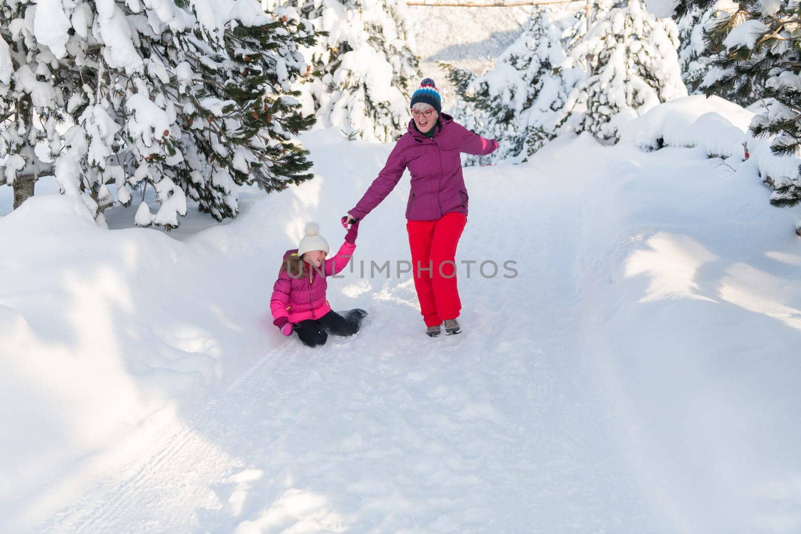 A mother and daughter as they dash along a serene snowy path, embracing the tranquil beauty of their winter mountain getaway.