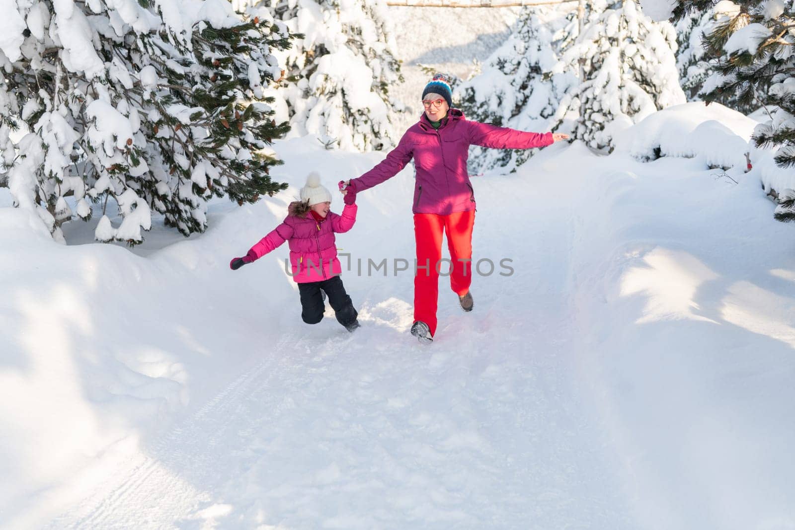 A Mother and Daughter's Blissful Run Along a Snowy Winter Path by dotshock