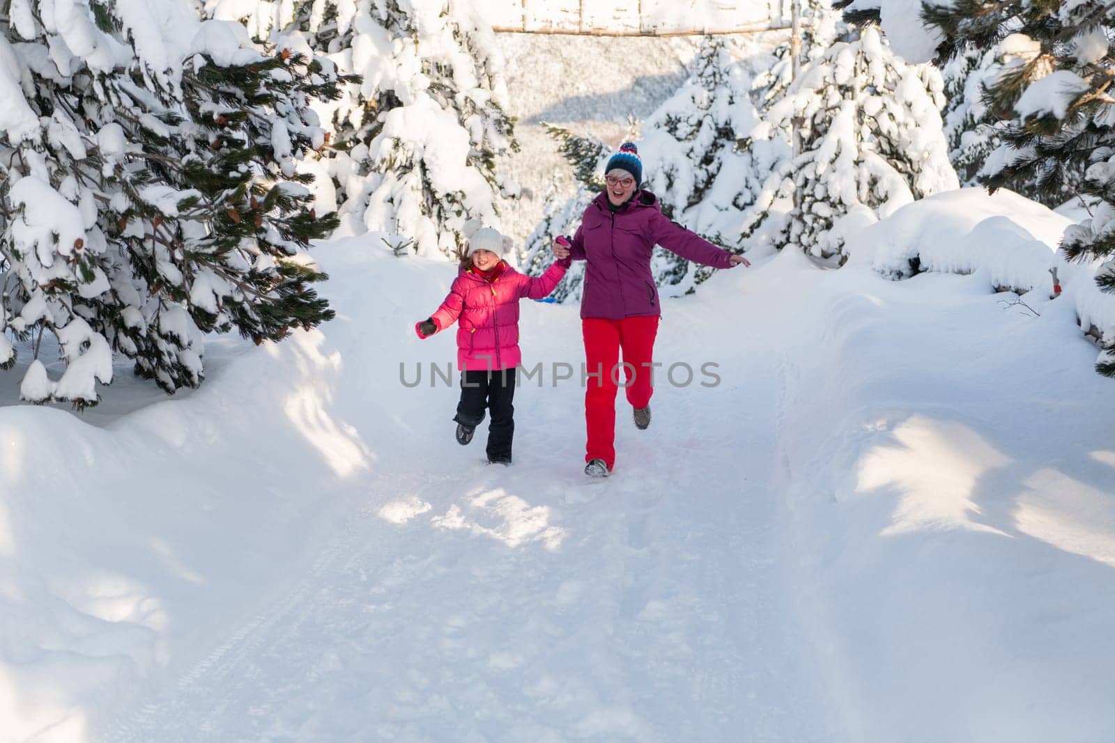 A Mother and Daughter's Blissful Run Along a Snowy Winter Path by dotshock