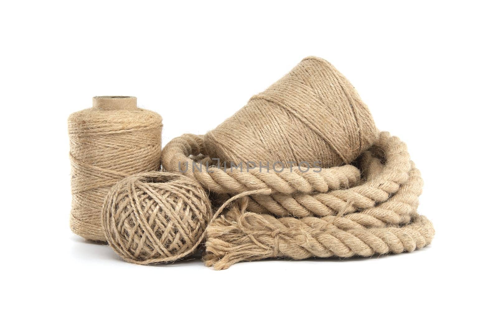 Collection of various rolls of natural jute rough rope and twine arranged on a white surface