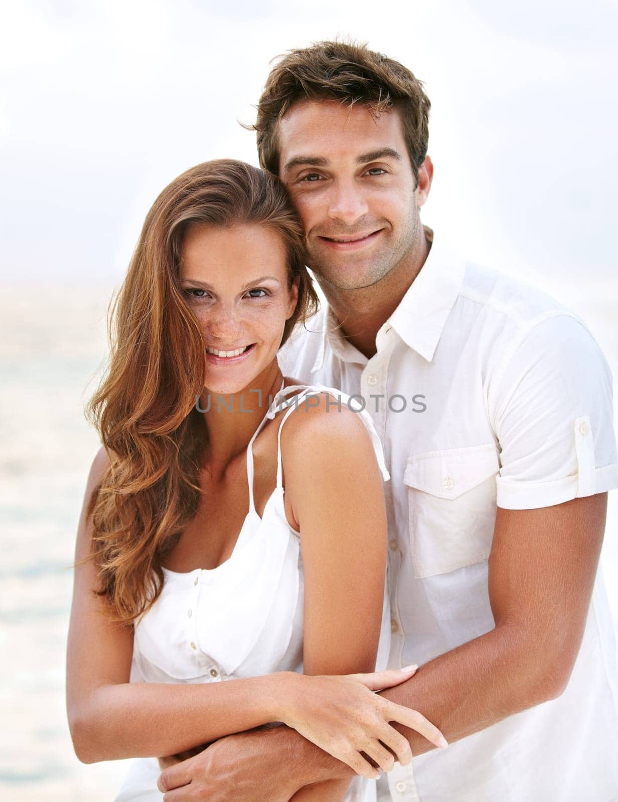 Happy couple, portrait and young love at beach, hug and travel on honeymoon adventure in sunshine. Man, woman and smile face for bonding in marriage, touch and together on ocean vacation in cape town.