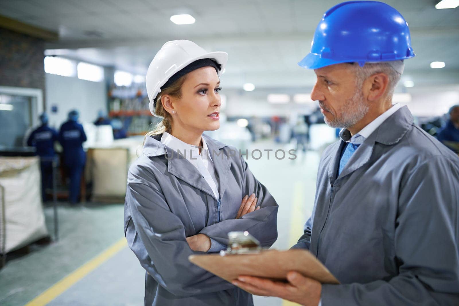 Man, woman and communication with clipboard in factory for quality inspection or safety checks and process monitoring. Team, conversation and board for manufacturing information in printing warehouse.