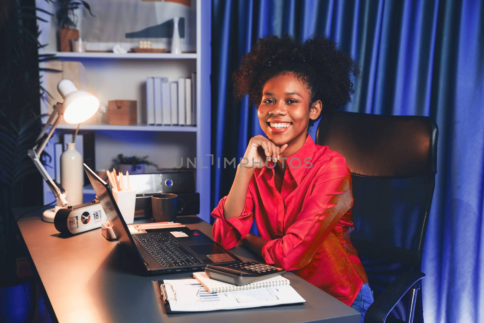 African woman blogger wearing pink shirt with happy face, looking on screen laptop with valued achievement project or get scholarship. Concept of cheerful expression work from home. Tastemaker.