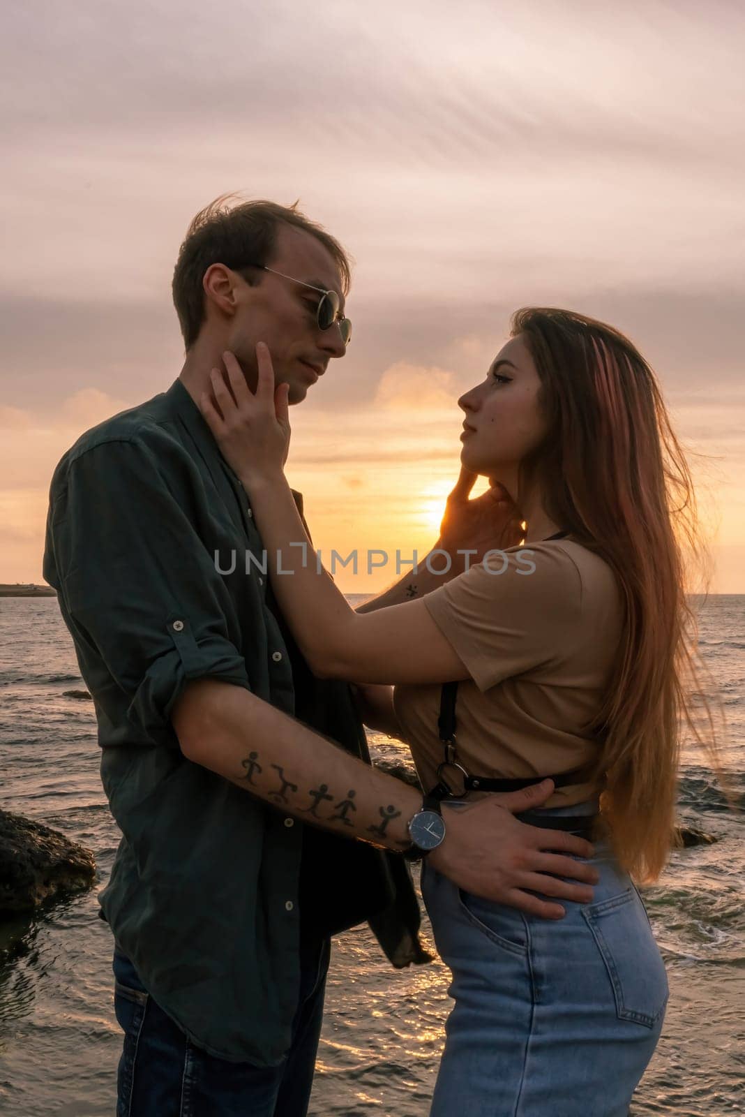 silhouettes in love romantic couple lovers hugging, kissing, touching, eye contact at sunset, sunrise on the background of the sea, the sun, the clouds in fiery red, orange colors by Matiunina