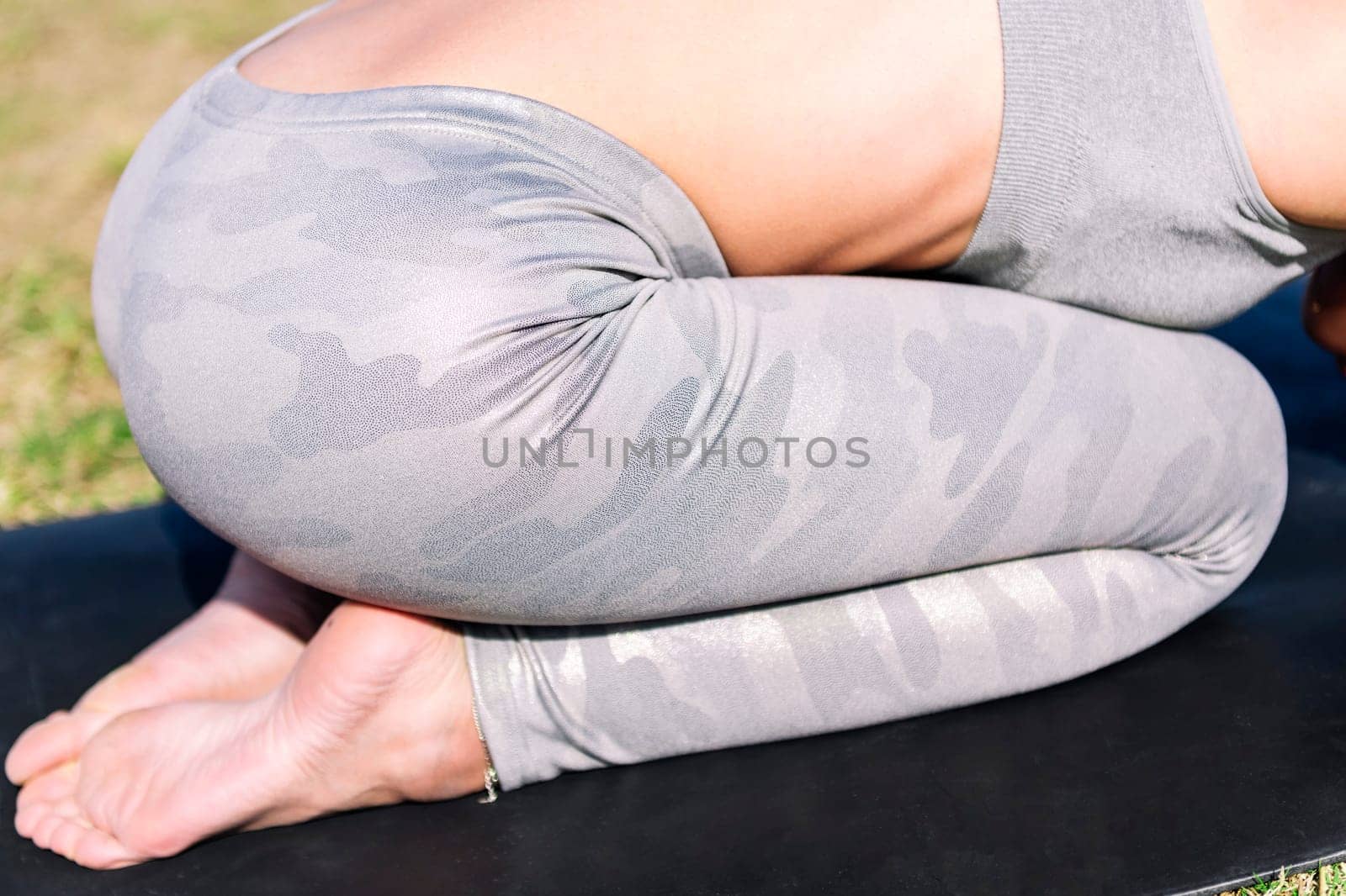 close up detail of the legs of an unrecognizable young woman in sportswear kneeling on her yoga mat doing stretching exercises, active and healthy lifestyle concept