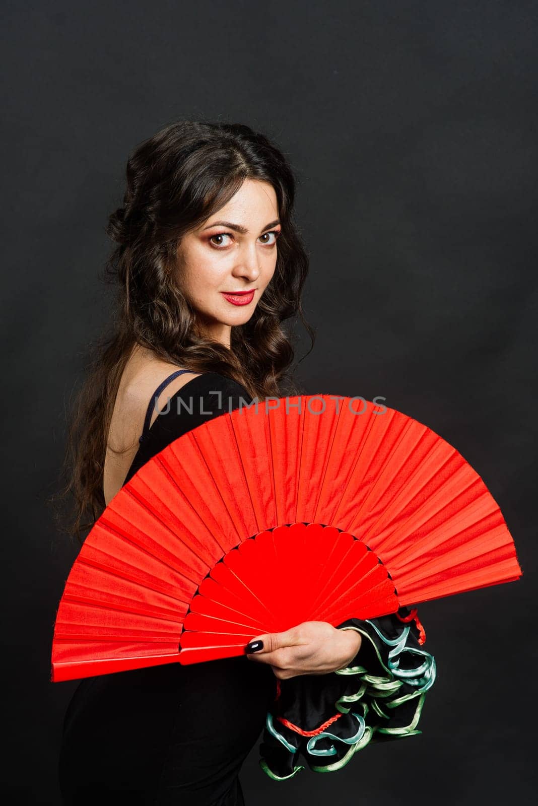 Portrait of beautiful young woman dancing flamenco with fan in studio