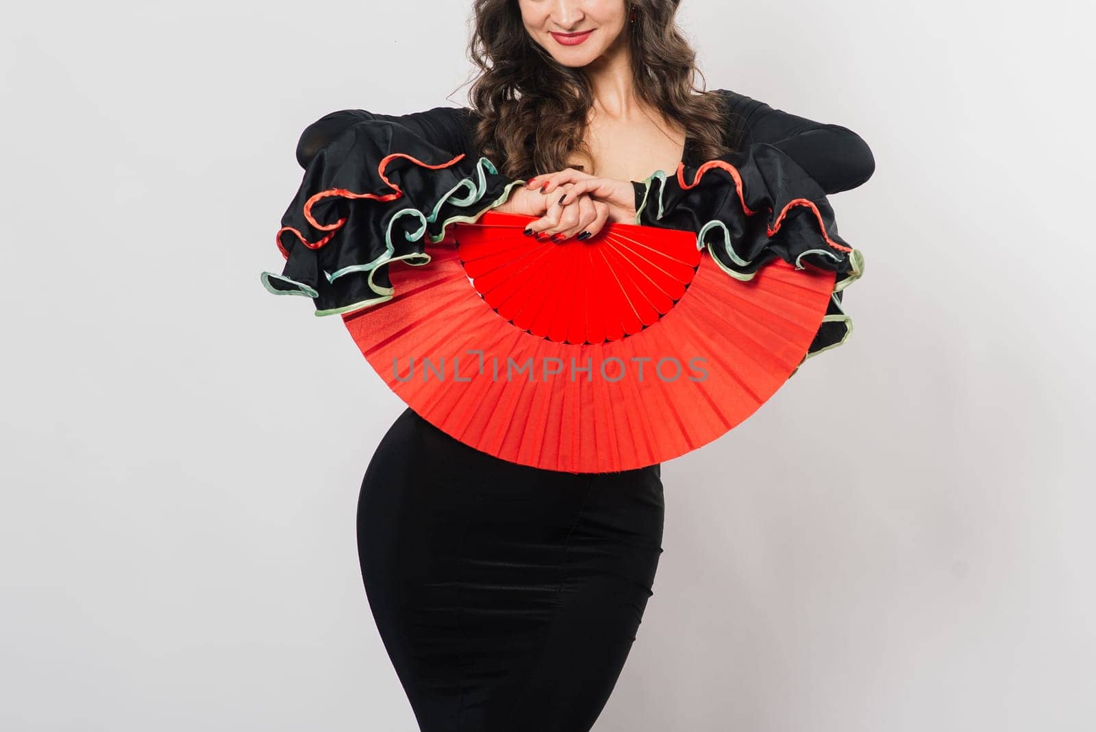 Portrait of beautiful young woman dancing flamenco with fan in studio