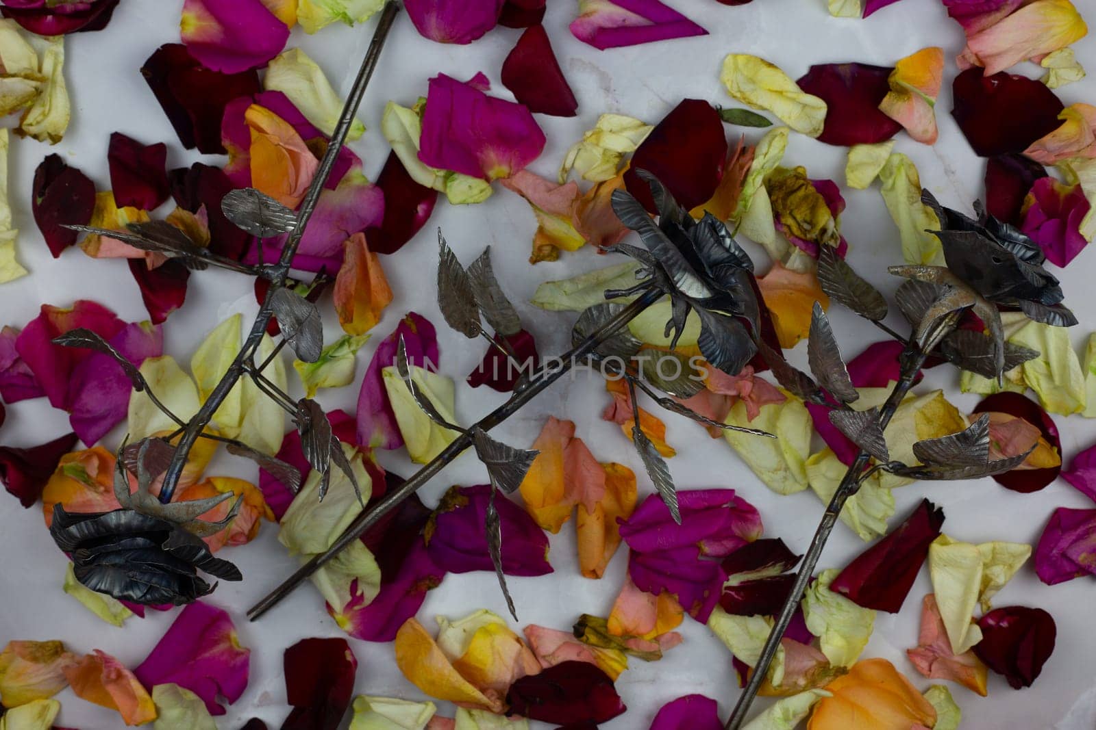 Unusual flowers for gift, metal roses against background of fresh flower petals