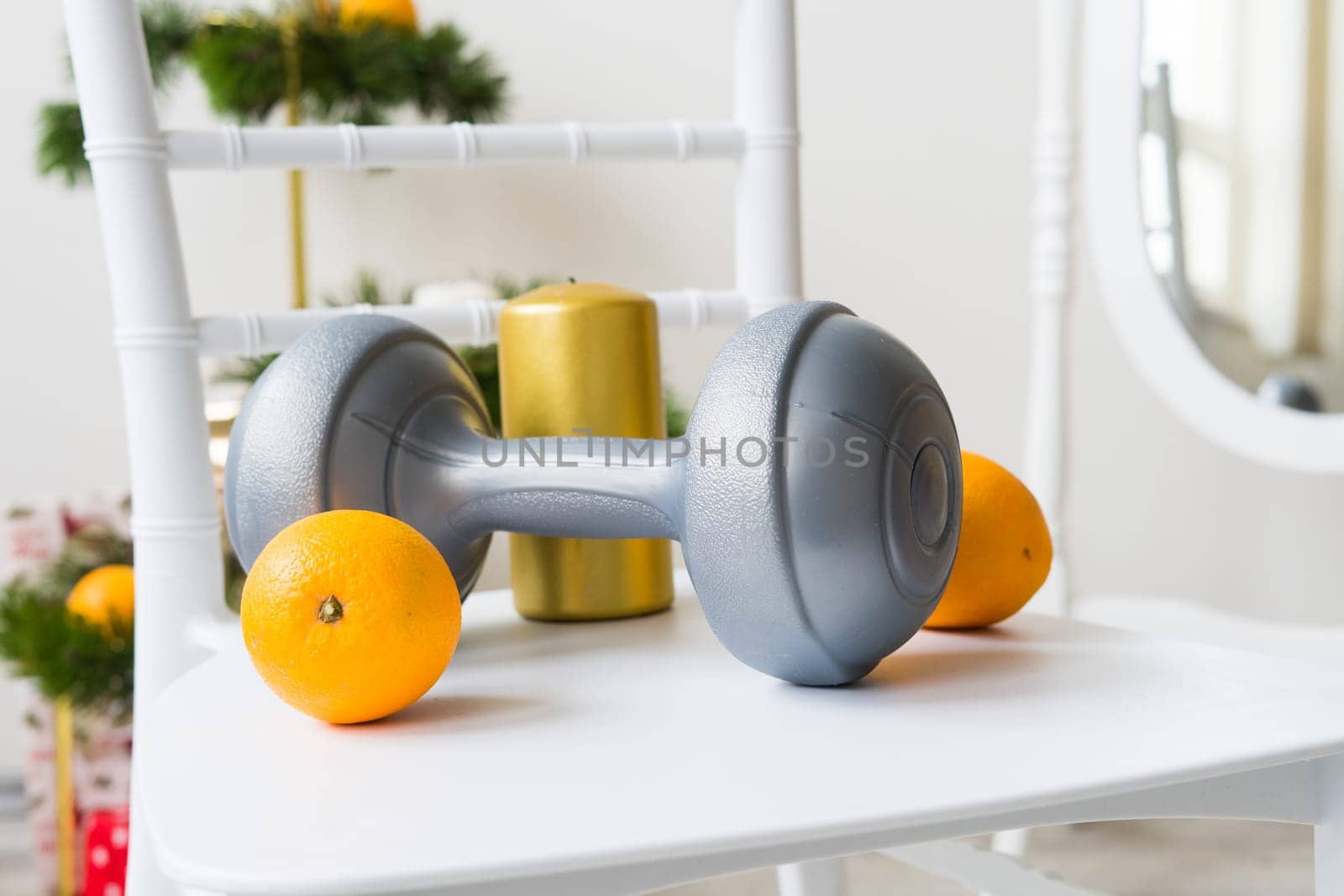 Sports equipment: dumbbell, boxing gloves, fir branch, Christmas ornament, gifts on chair. by Zelenin