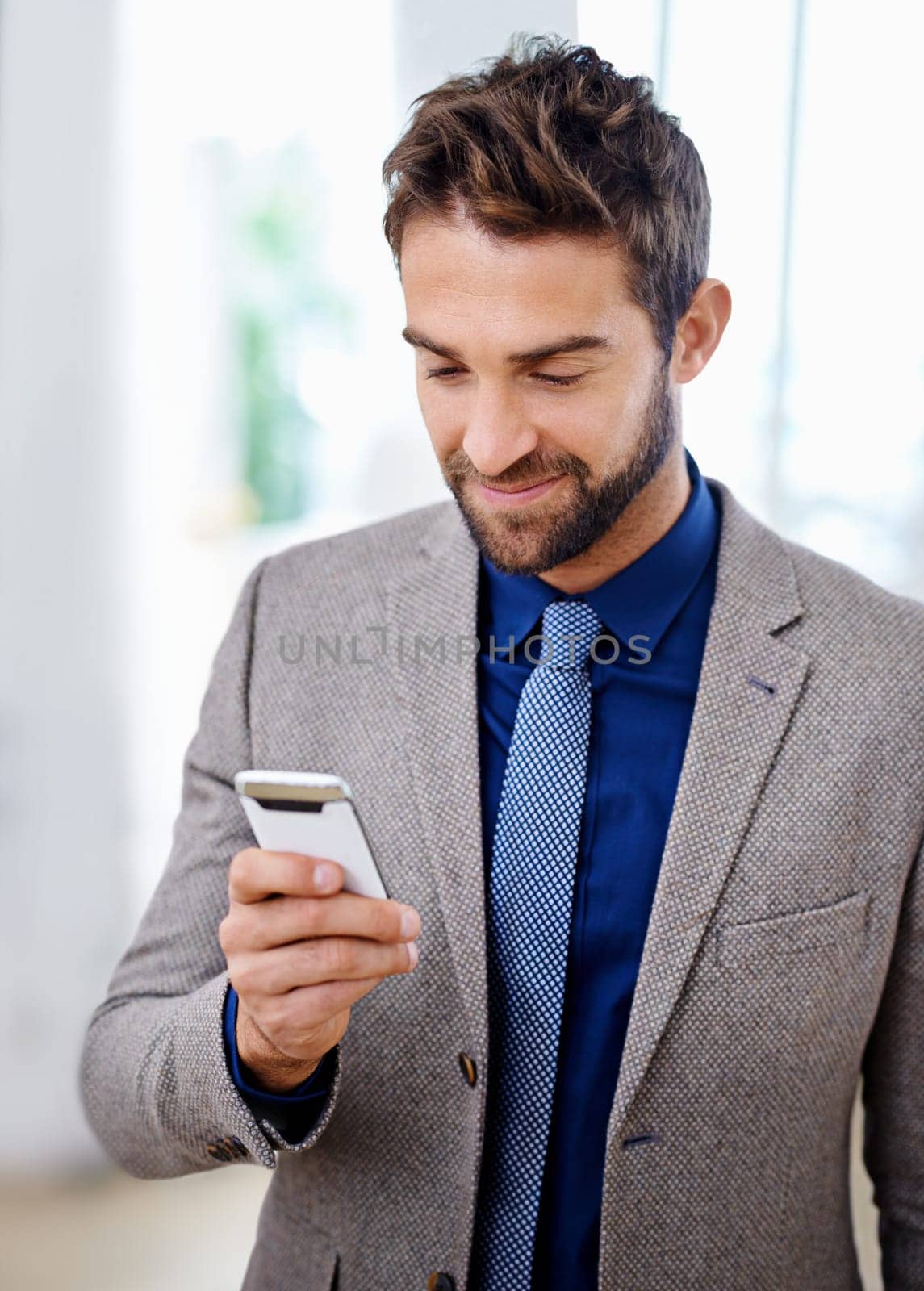 Business man, phone and typing an email in office, communication and networking for company. Male person, smile and reading a notification on app for conversation, website and internet for info by YuriArcurs