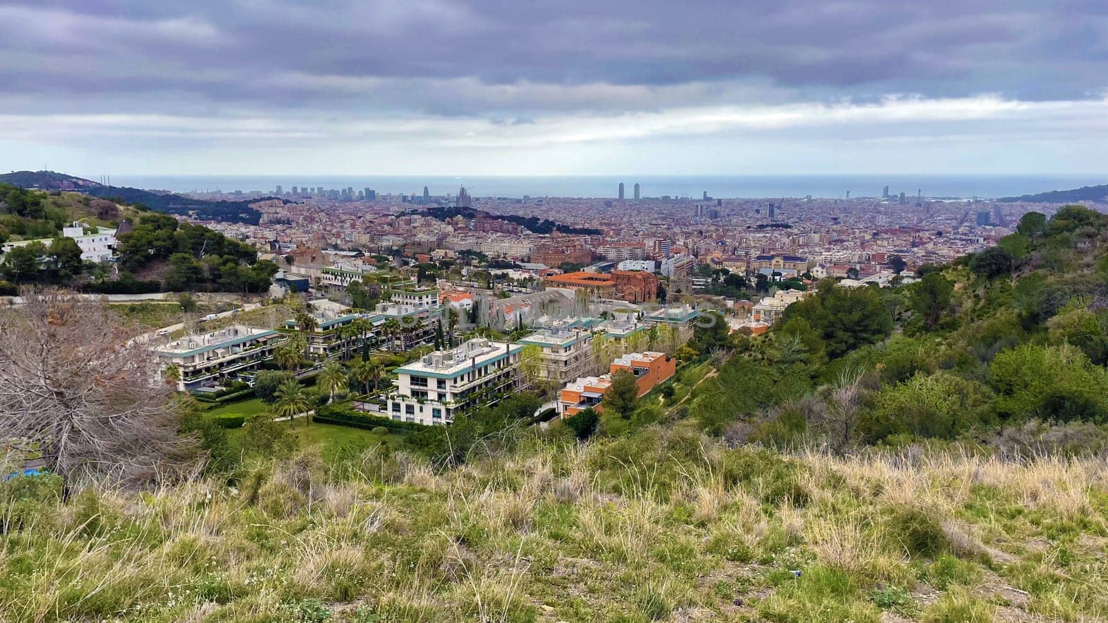 Panoramic view of Barcelona city from the hill, rainy weather landscape by Iakimova