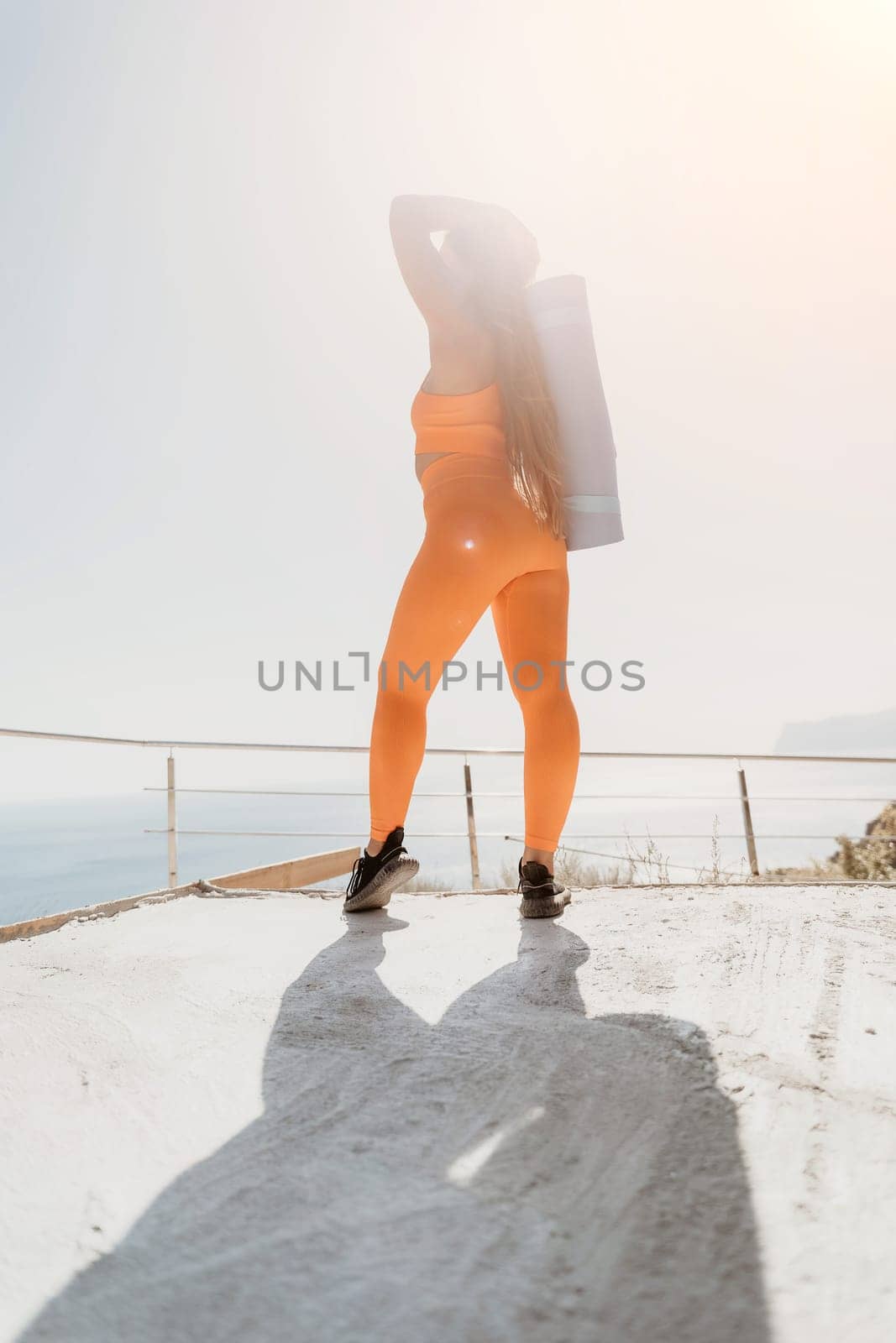 Fitness woman sea. Outdoor workout on yoga mat in park near to ocean beach. Female fitness pilates yoga routine concept. Healthy lifestyle. Happy fit woman exercising with rubber band in park.