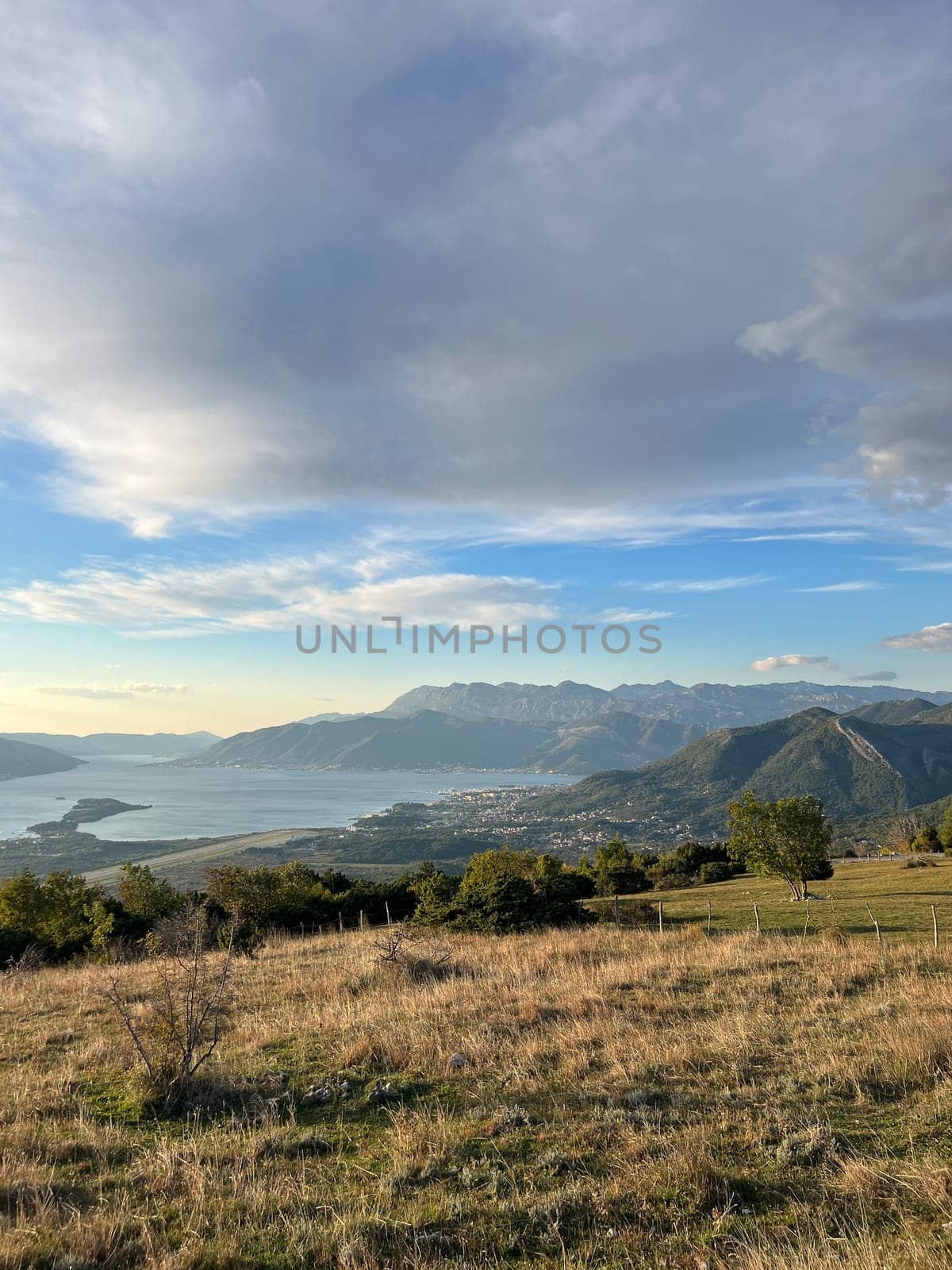 Green meadow above the sea surrounded by a mountain range by Nadtochiy