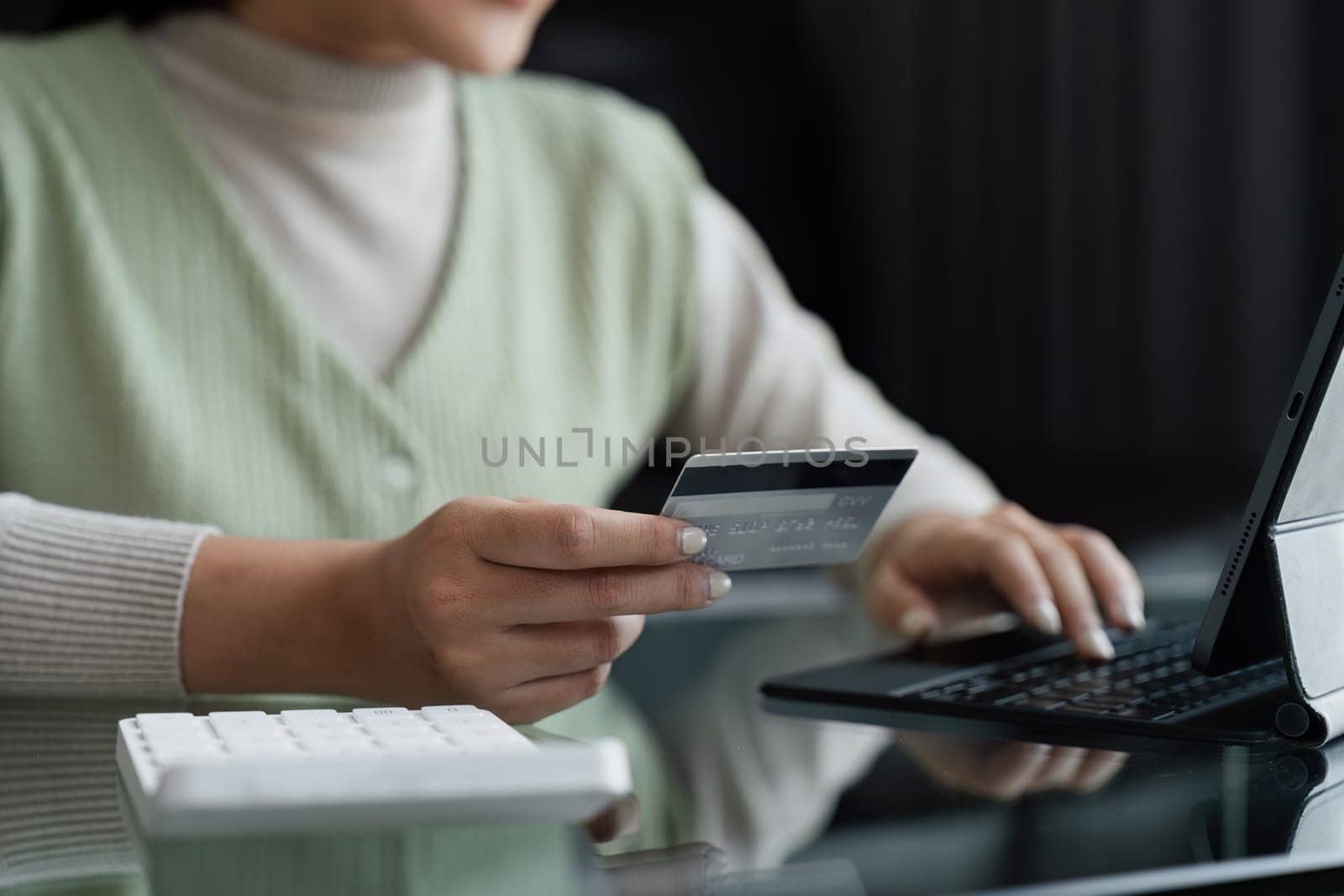 Asian woman using credit card for purchasing and shopping online on tablet.