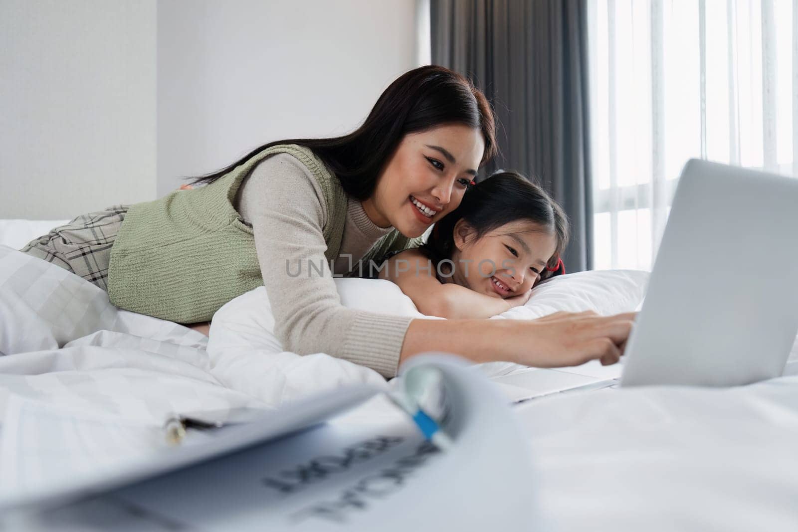businessman sit on bed doing document brought home from work while taking care child.