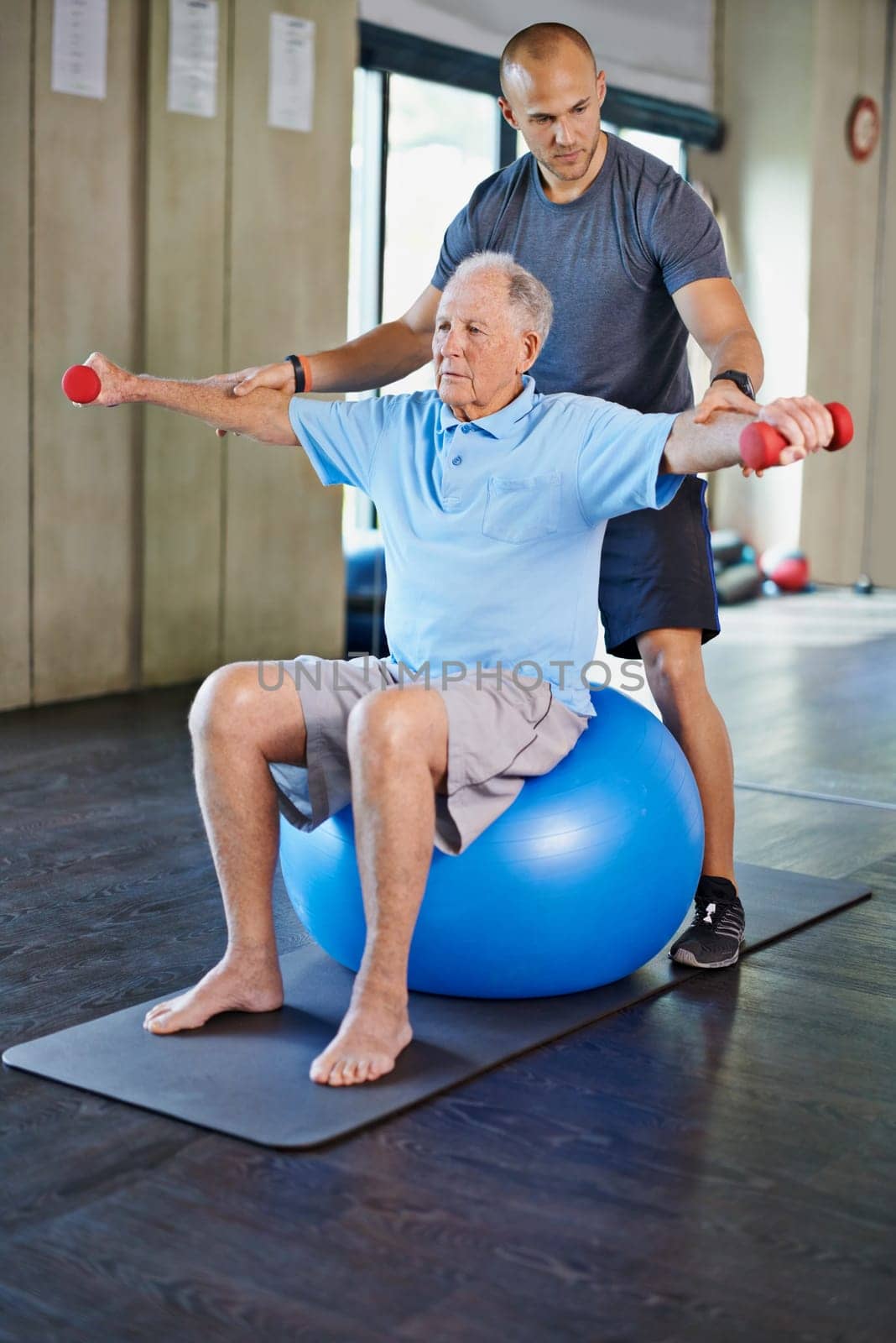 Physiotherapist, helping and senior man with weights, training and elderly support for care. Men, gym and exercise for health, wellness and coaching with yoga ball for mature rehab and wellbeing by YuriArcurs
