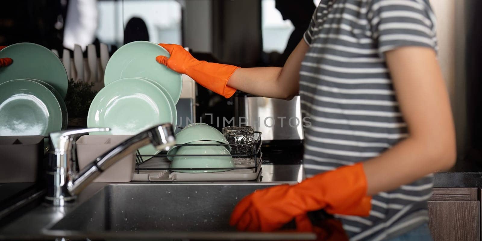 Woman washing up at home dishes in sink.