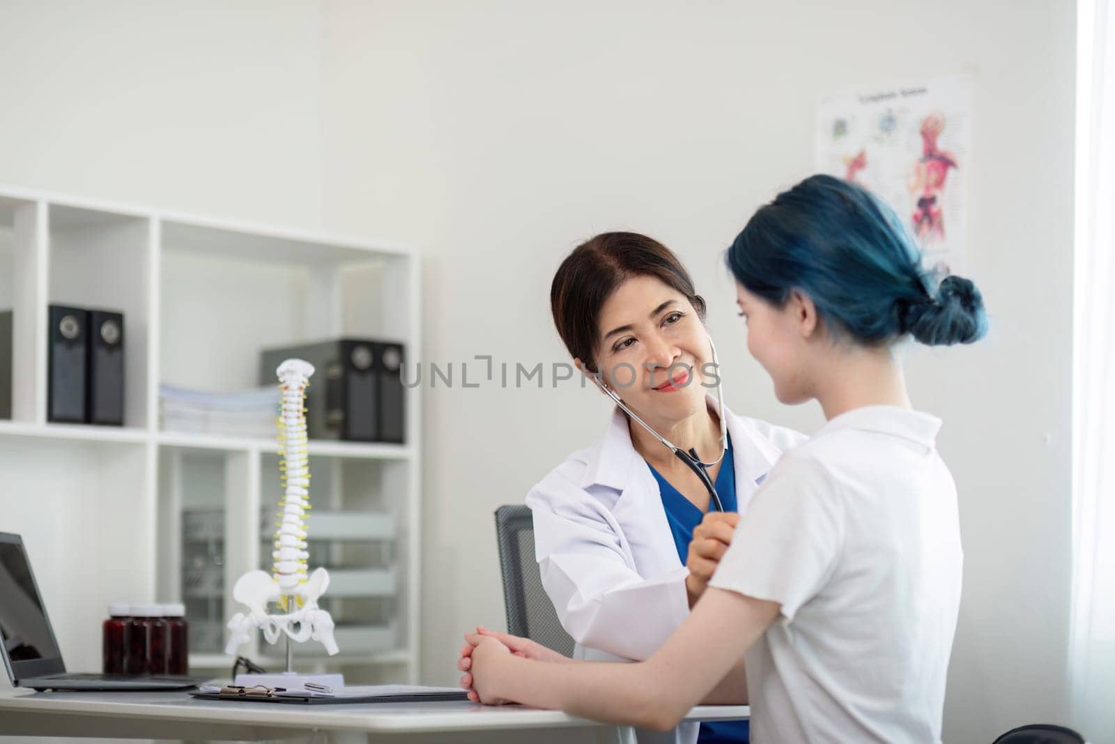 Asian woman elderly doctor at hospital taking care of young woman. Doctor measure heart rate by stethoscope on older patient. Medical insurance service concept by nateemee