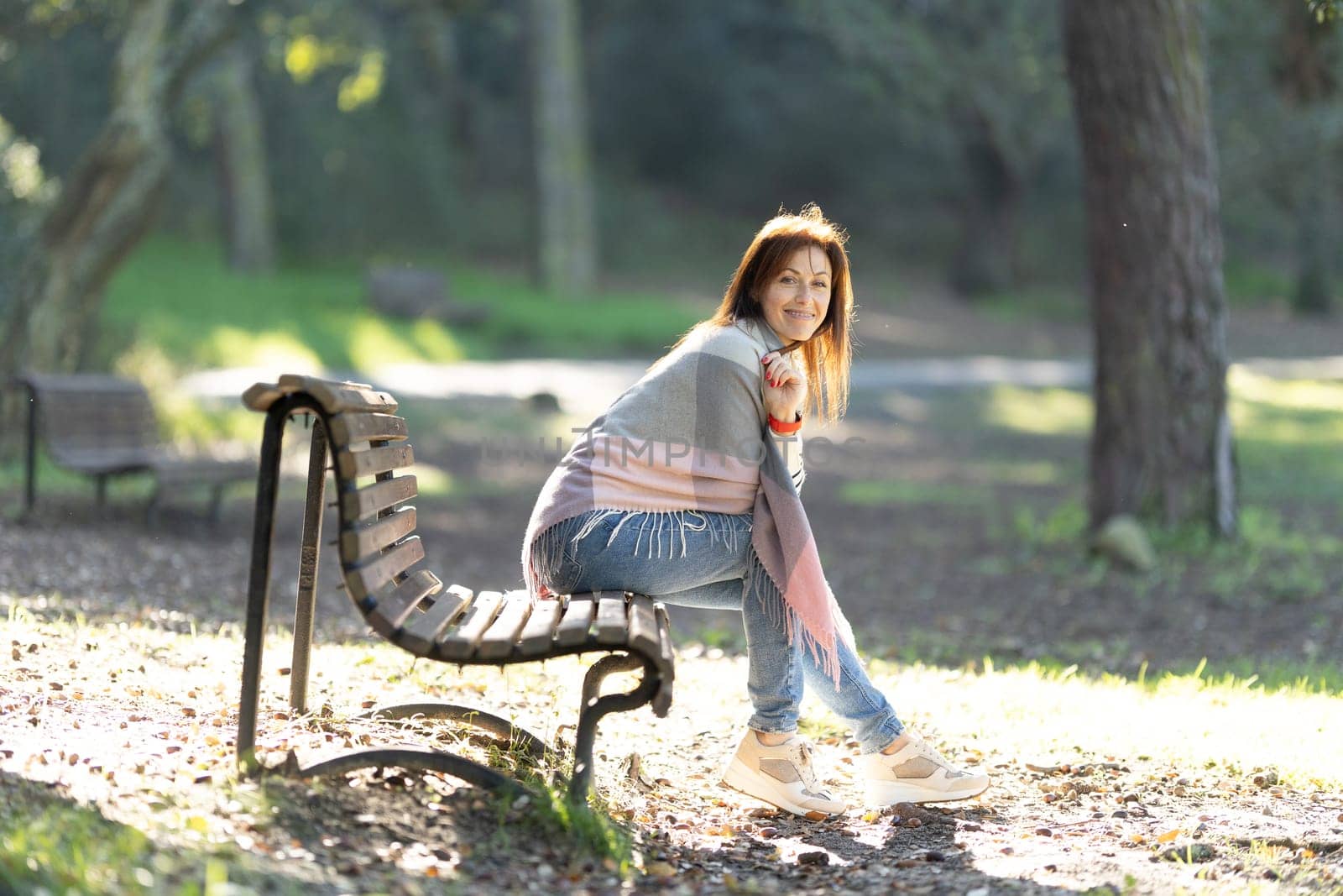 A woman is sitting on a park bench, wearing a scarf and a pink shirt by Studia72