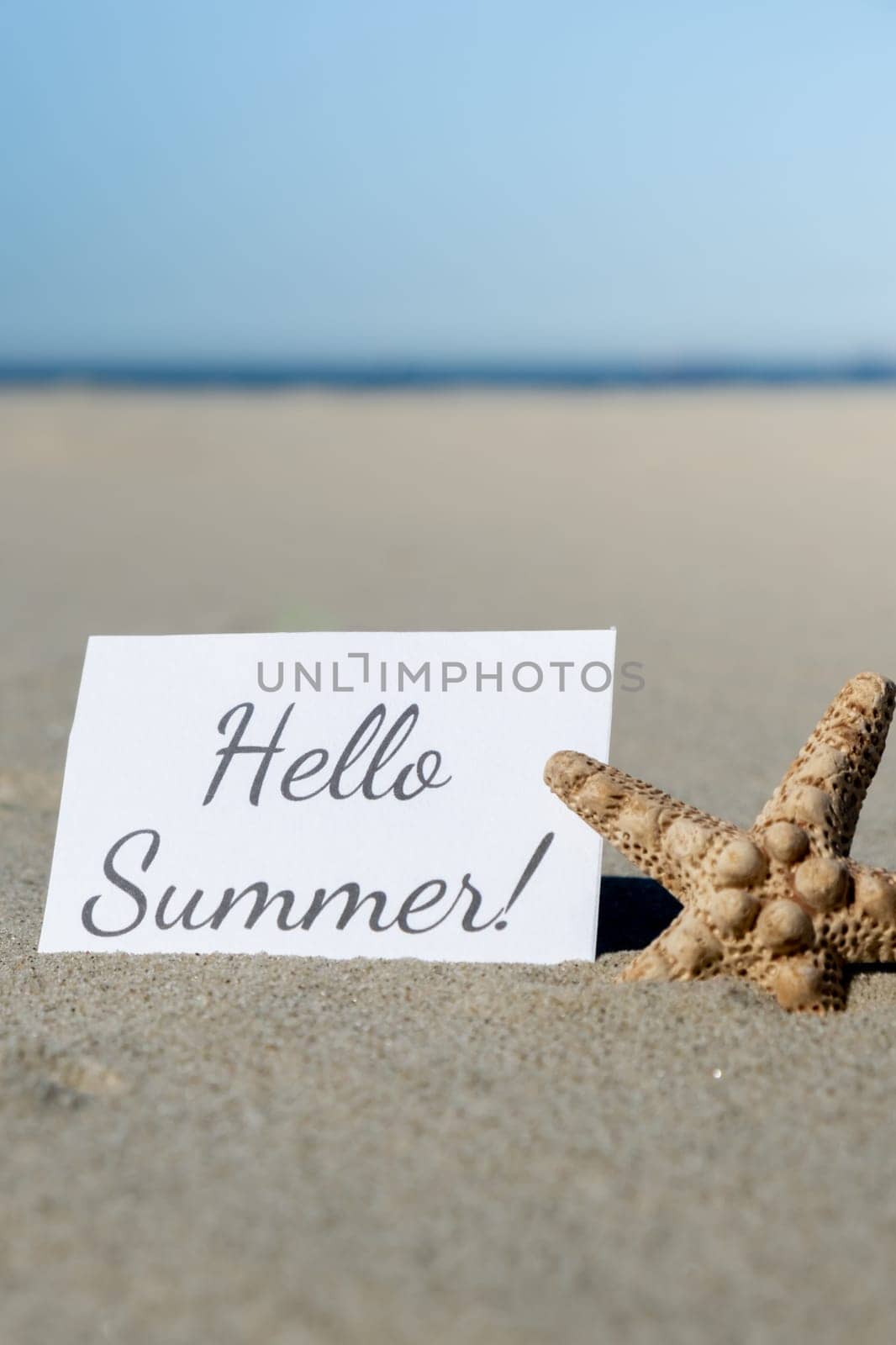HELLO SUMMER text on paper greeting card on background of starfish seashell summer vacation decor. Sandy beach sun coast. Holiday concept postcard. Getting away Travel Business concept