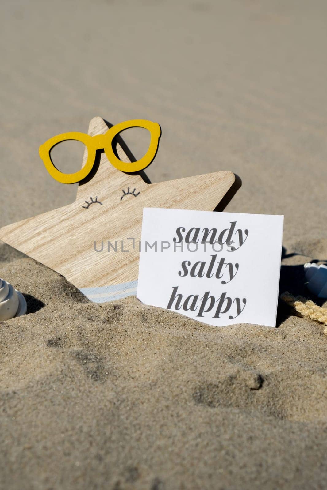 SANDY SALTY HAPPY text on paper greeting card on background of funny starfish in glasses summer vacation decor. Beach sun coast. Slowing-down, enjoying the moment, good moments, slow life Holiday concept postcard. Getting away Travel Business concept