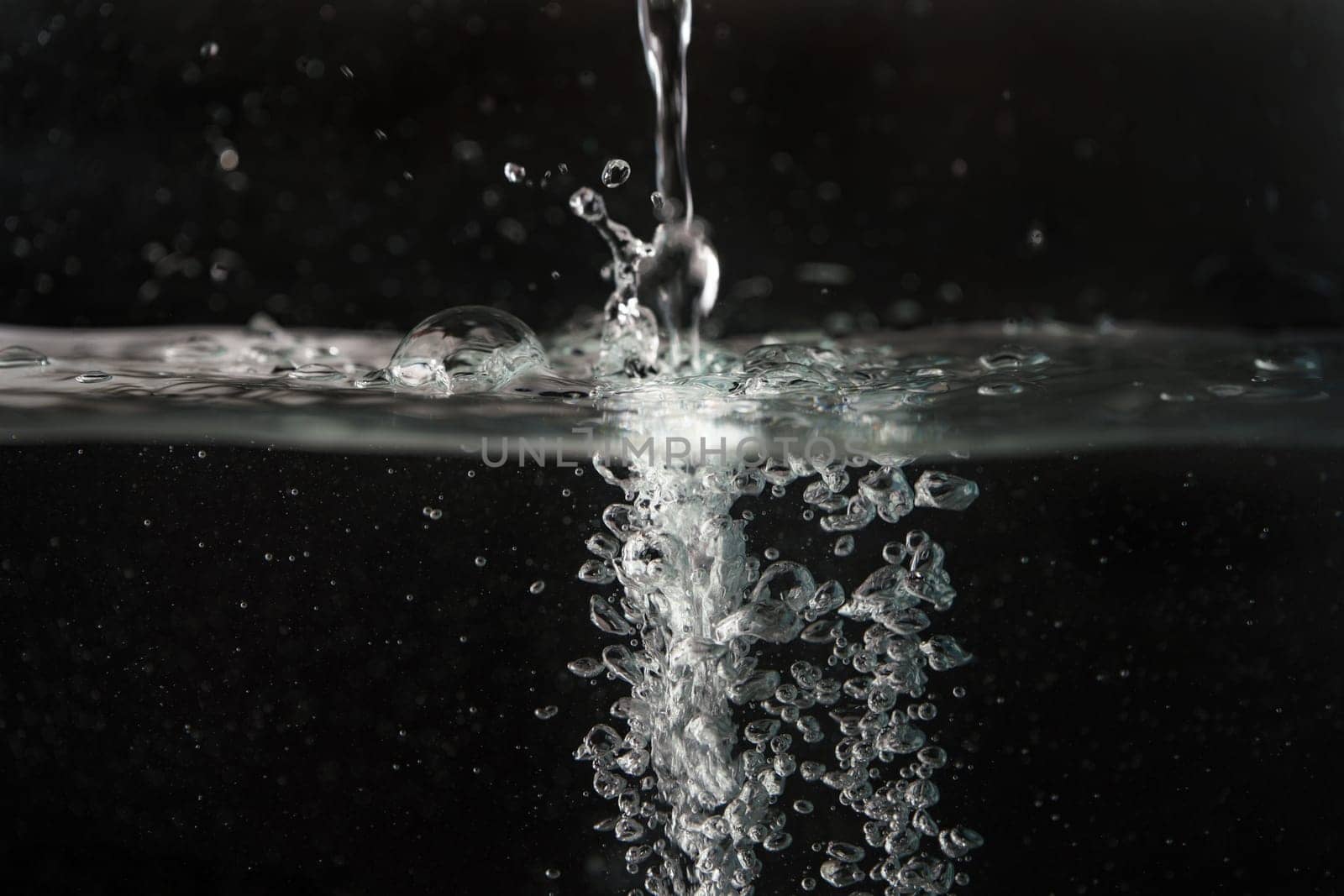 Water splashing as it's poured into aquarium tank, black background