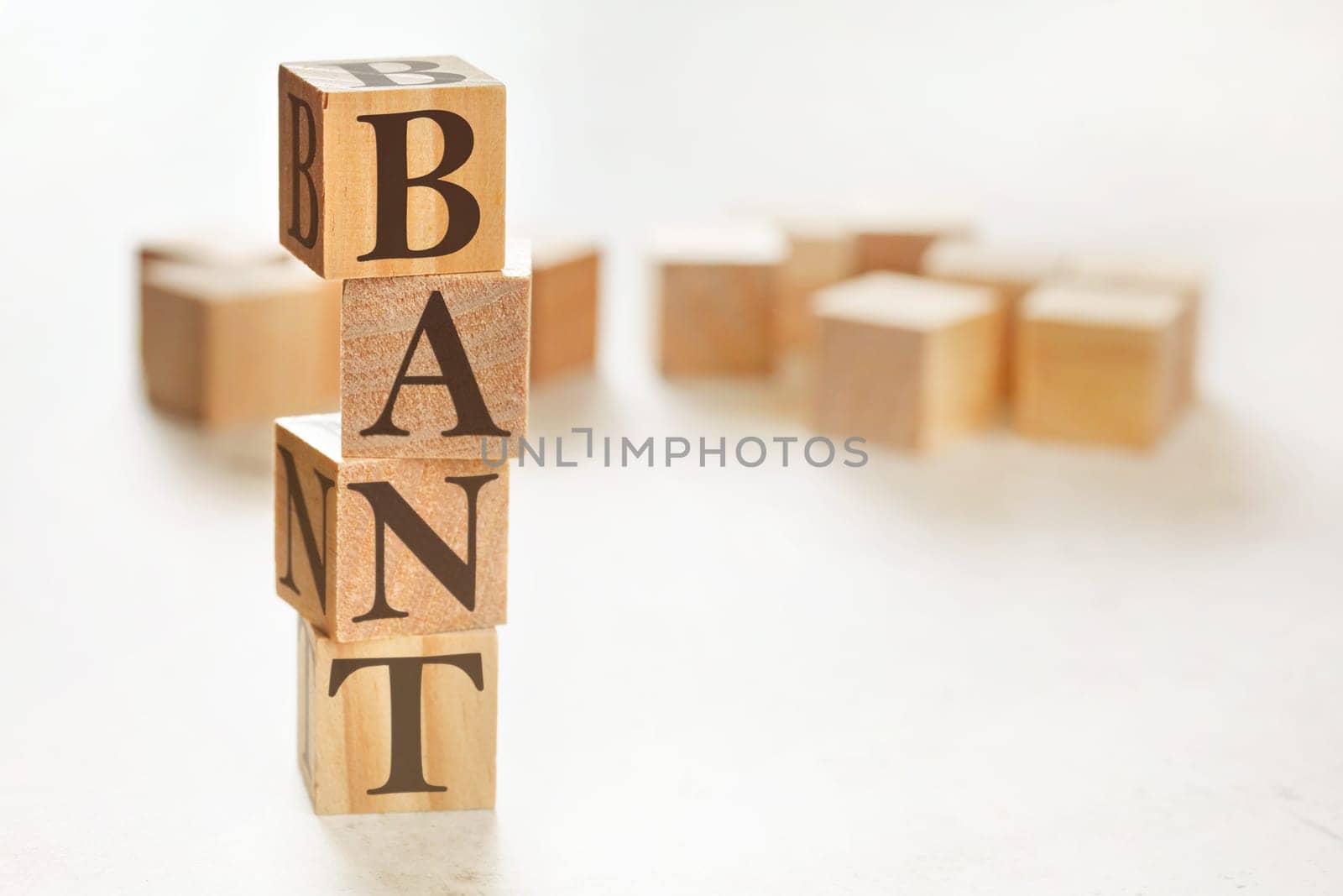 Four wooden cubes arranged in stack with letters BANT (acronym for Budget Authority Need Timeline) on them, space for text / image at down right corner