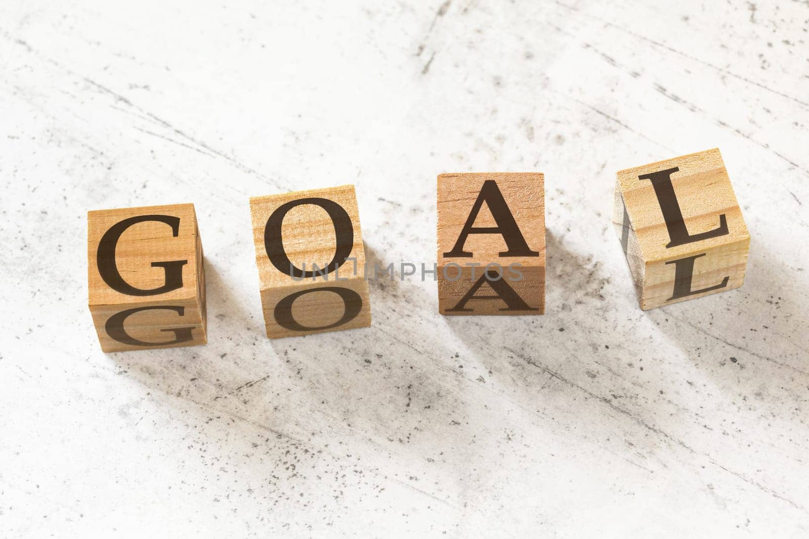 Four wooden cubes with word GOAL on white working board. by Ivanko