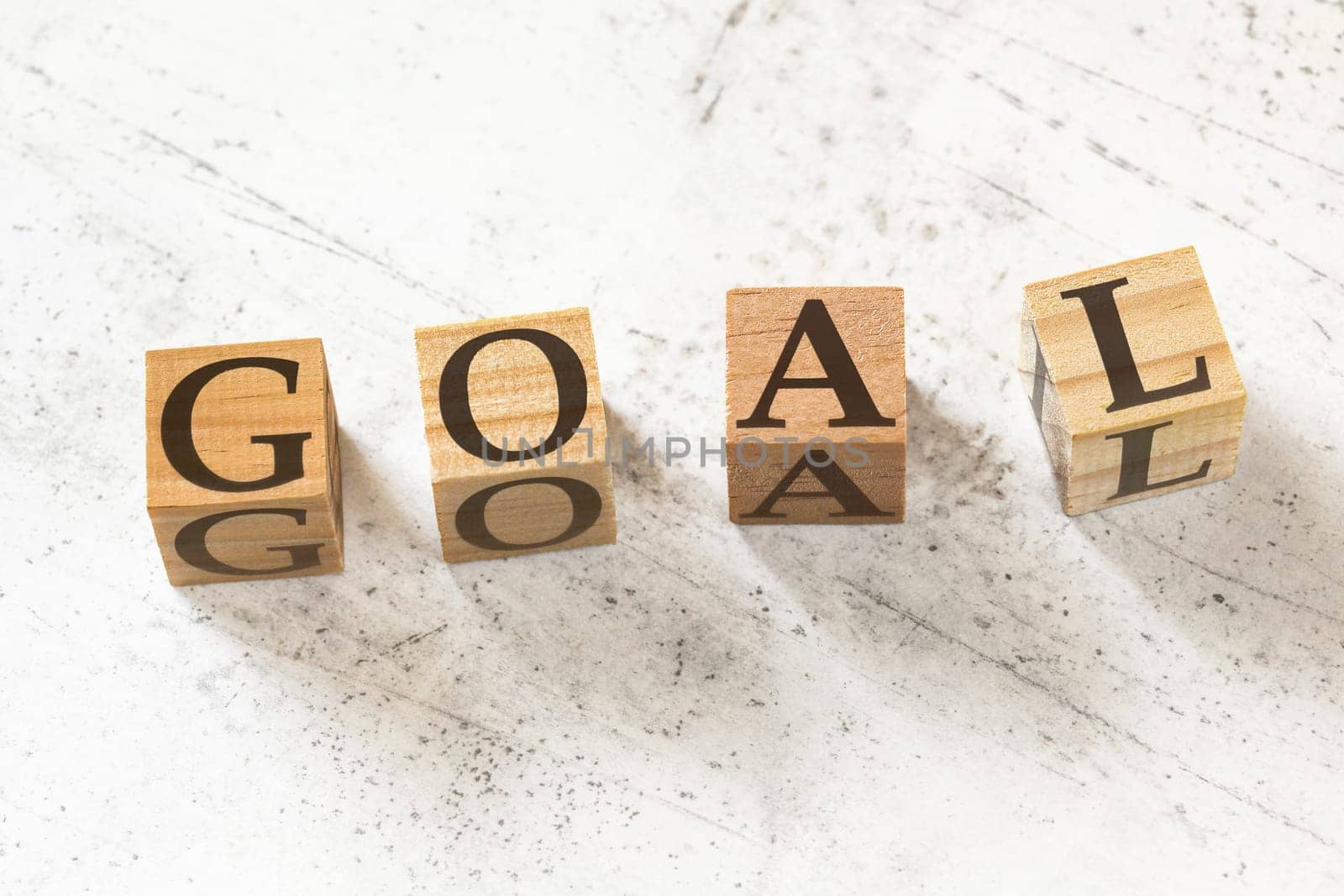 Four wooden cubes with word GOAL on white working board.