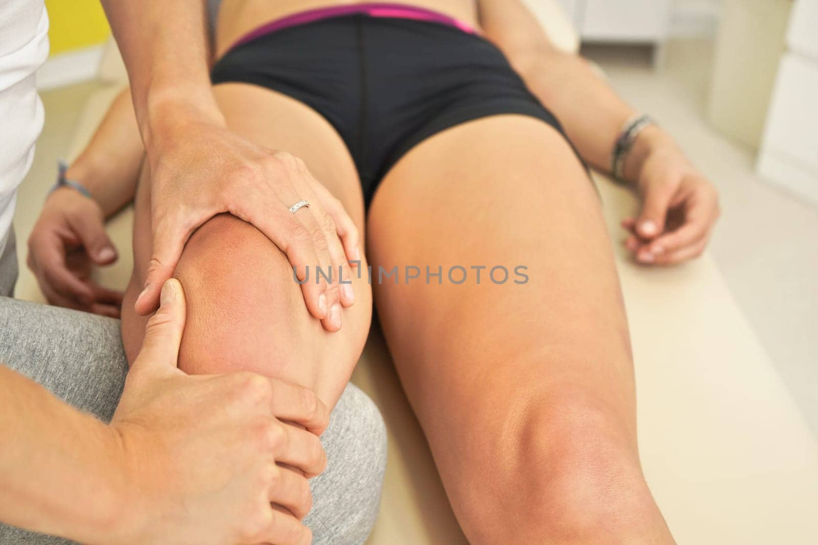 Physiotherapist massaging leg of her patient lying down on massage table by Ivanko