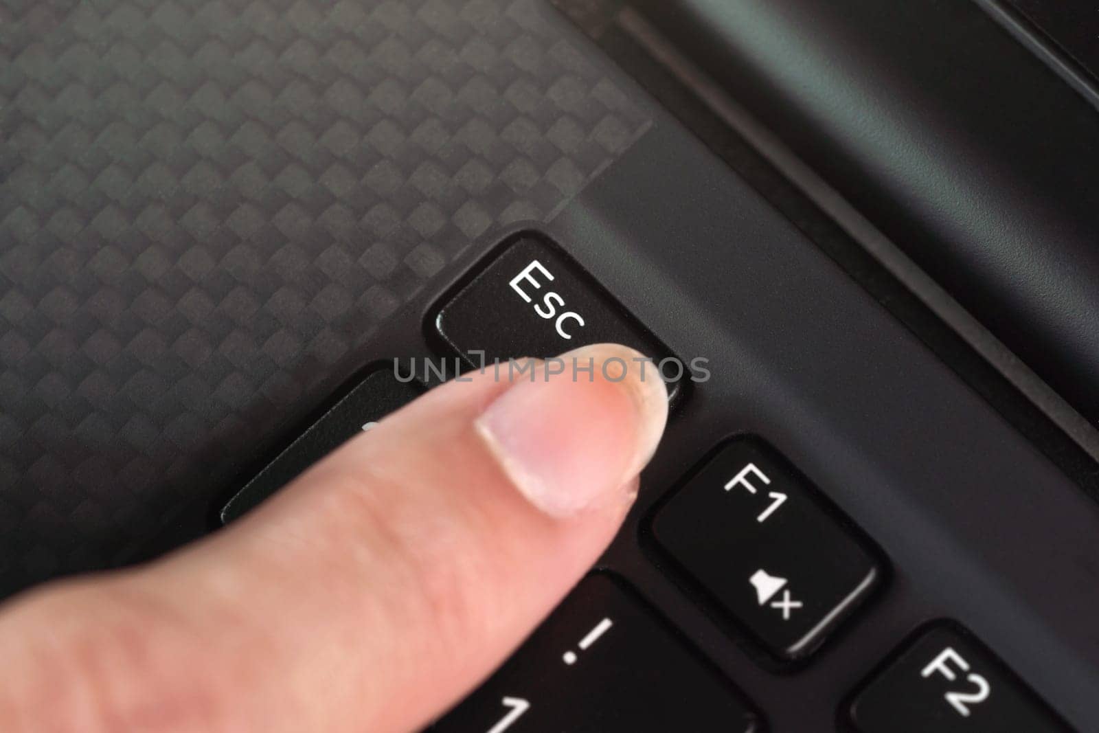 Detail on woman finger pressing the esc key on laptop keyboard