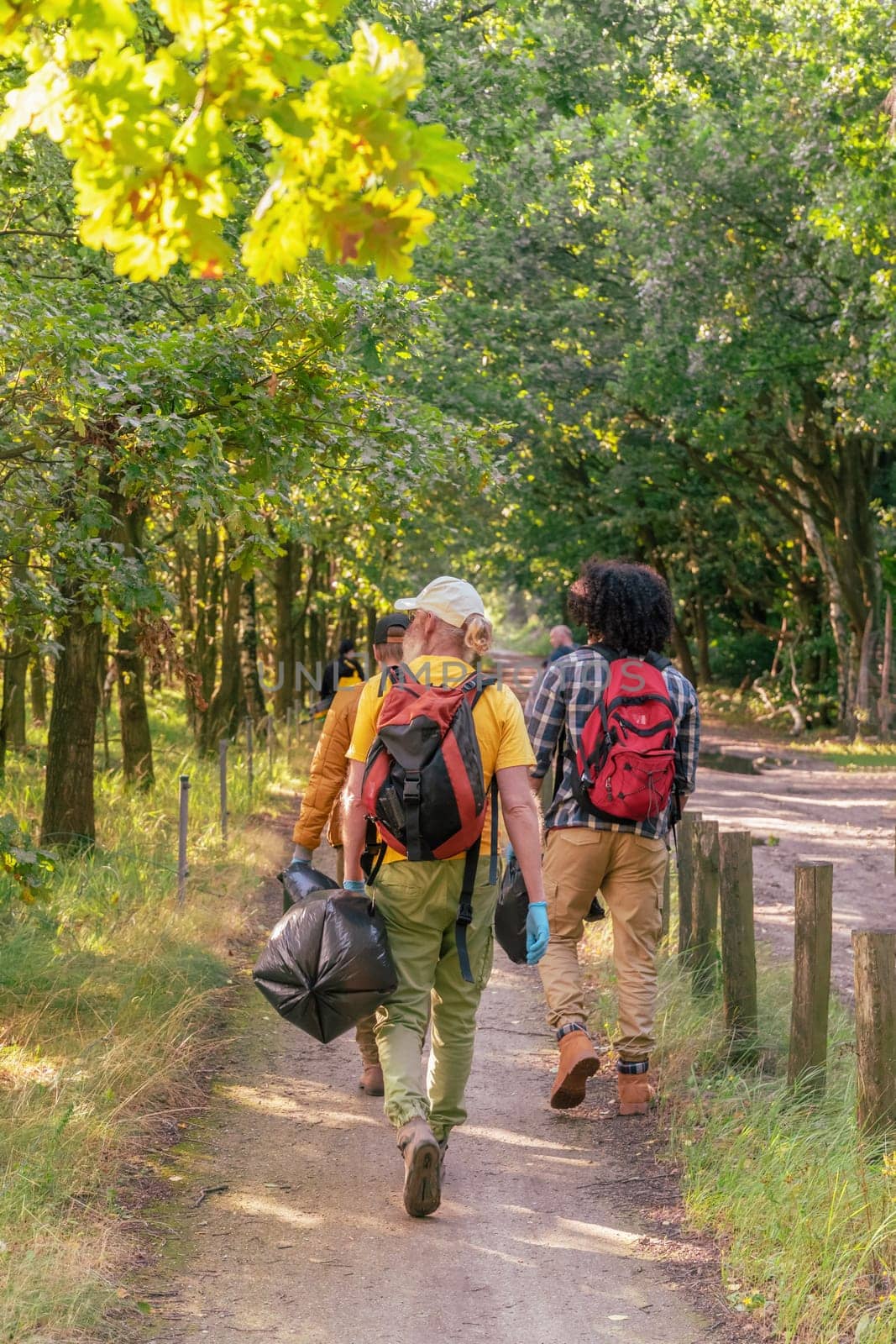 group of volunteer tourists dressed in comfortable hiking clothes walk together in the forest to collect garbage, carrying swords and gloves,the concept of ecology and cleanliness,High quality photo