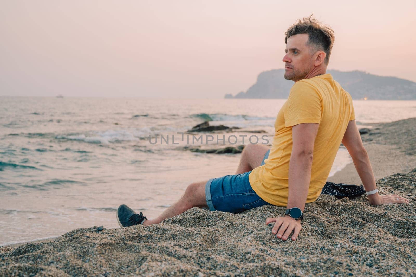 Man sits on the beach and looks at the sea in Alanya city by rusak