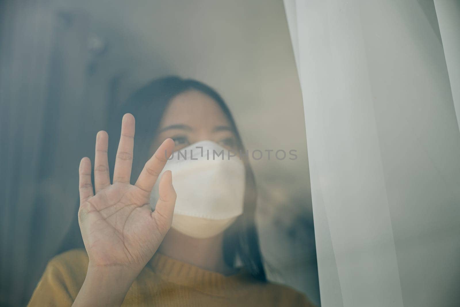 Highlighting self-isolation, Woman in a medical mask stays at home emphasizing COVID-19 prevention during the outbreak situation and the concept of home quarantine.
